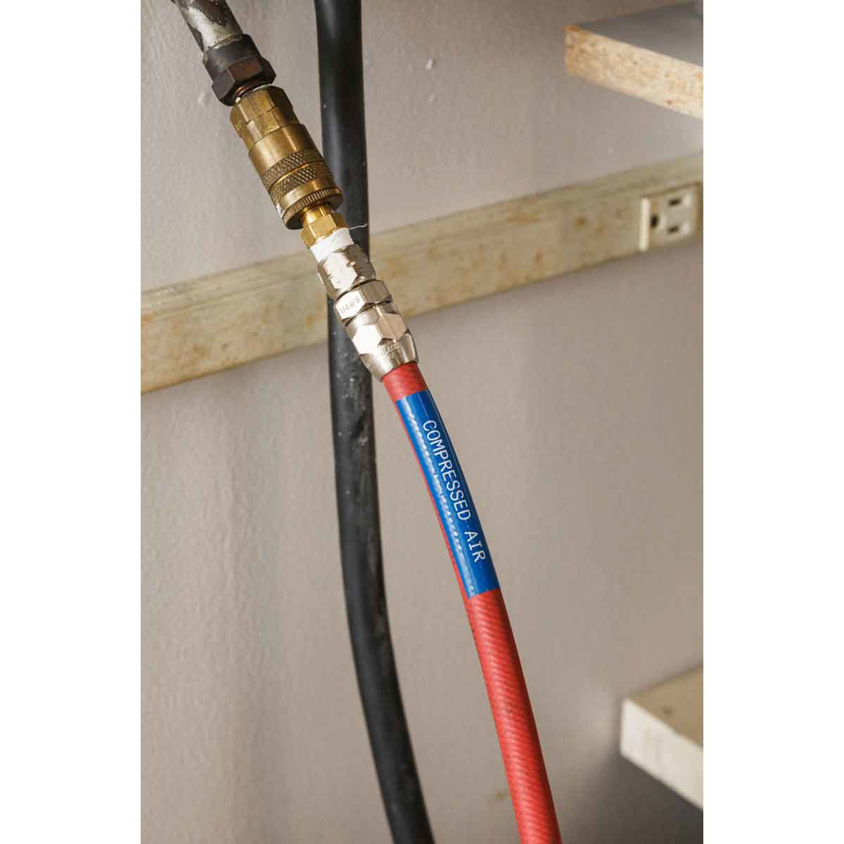 Tubo rosso per aria compressa collegato a tubo nero e presa a muro.