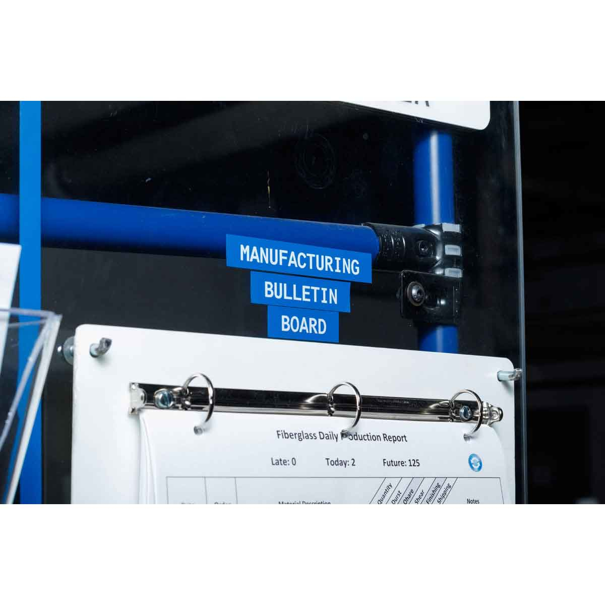 Un tabellone di produzione con etichette blu su pali blu, con un rapporto bianco sotto.