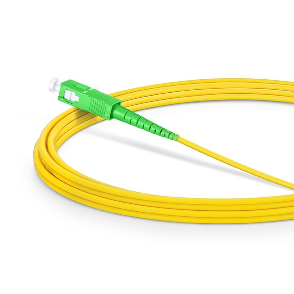Un cavo in fibra ottica giallo con un connettore verde, arrotolato su sfondo bianco.