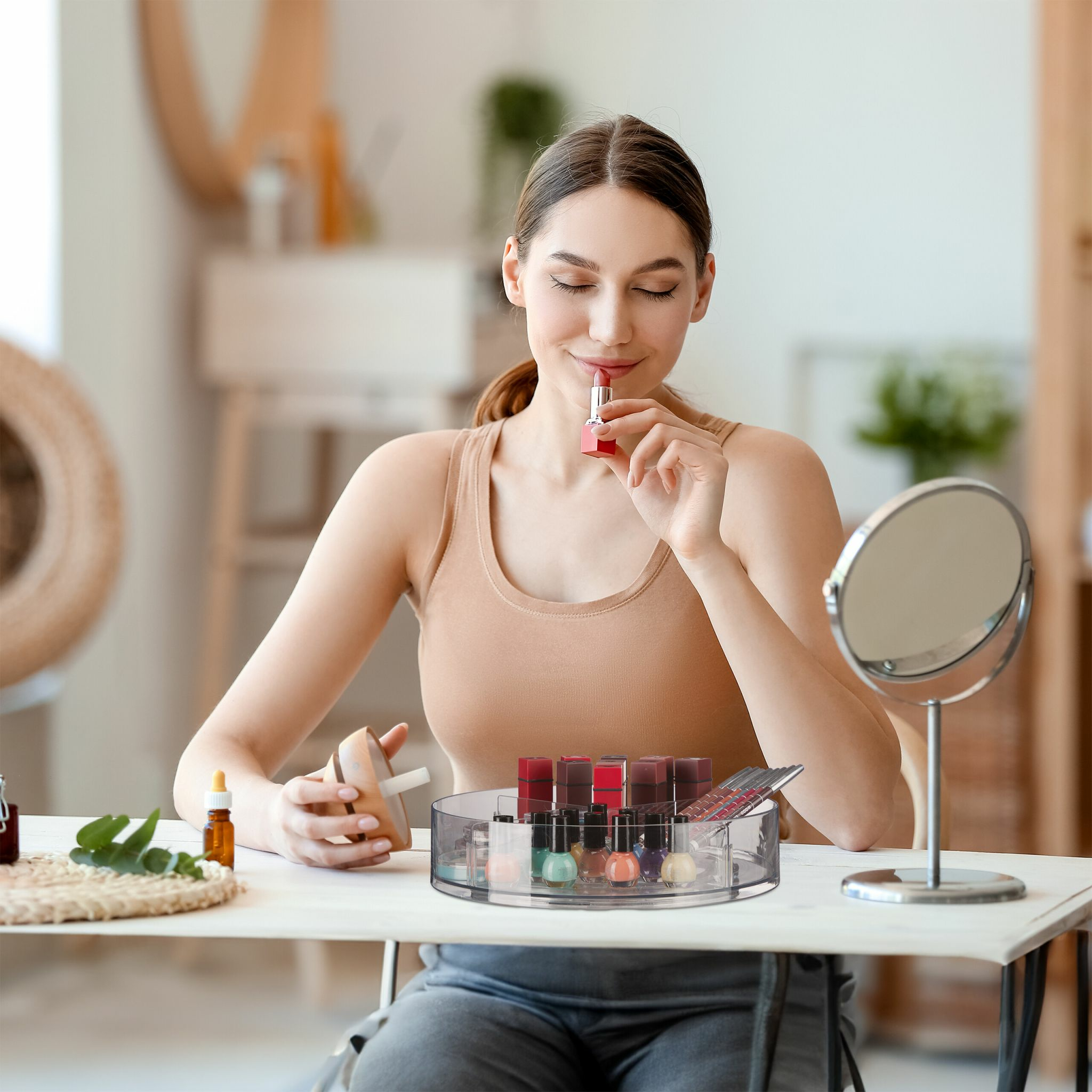 Une femme applique du rouge à lèvres tout en étant assise à une coiffeuse avec du maquillage et un miroir.