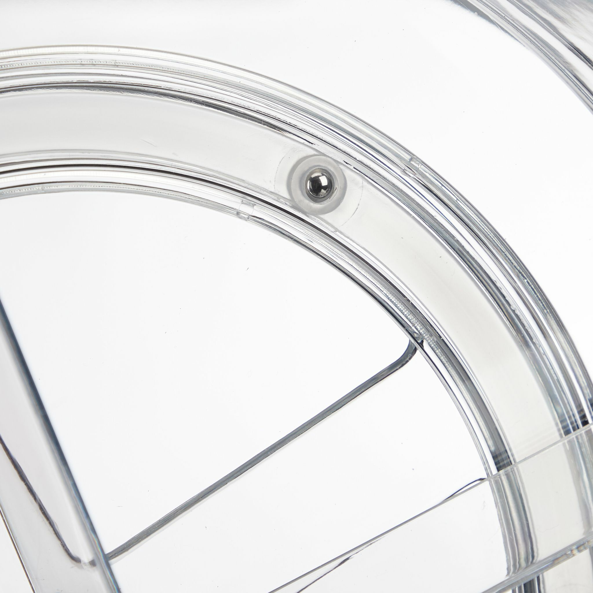 Segment de cercle en plastique transparent, avec une petite bille métallique en haut. Fond blanc.