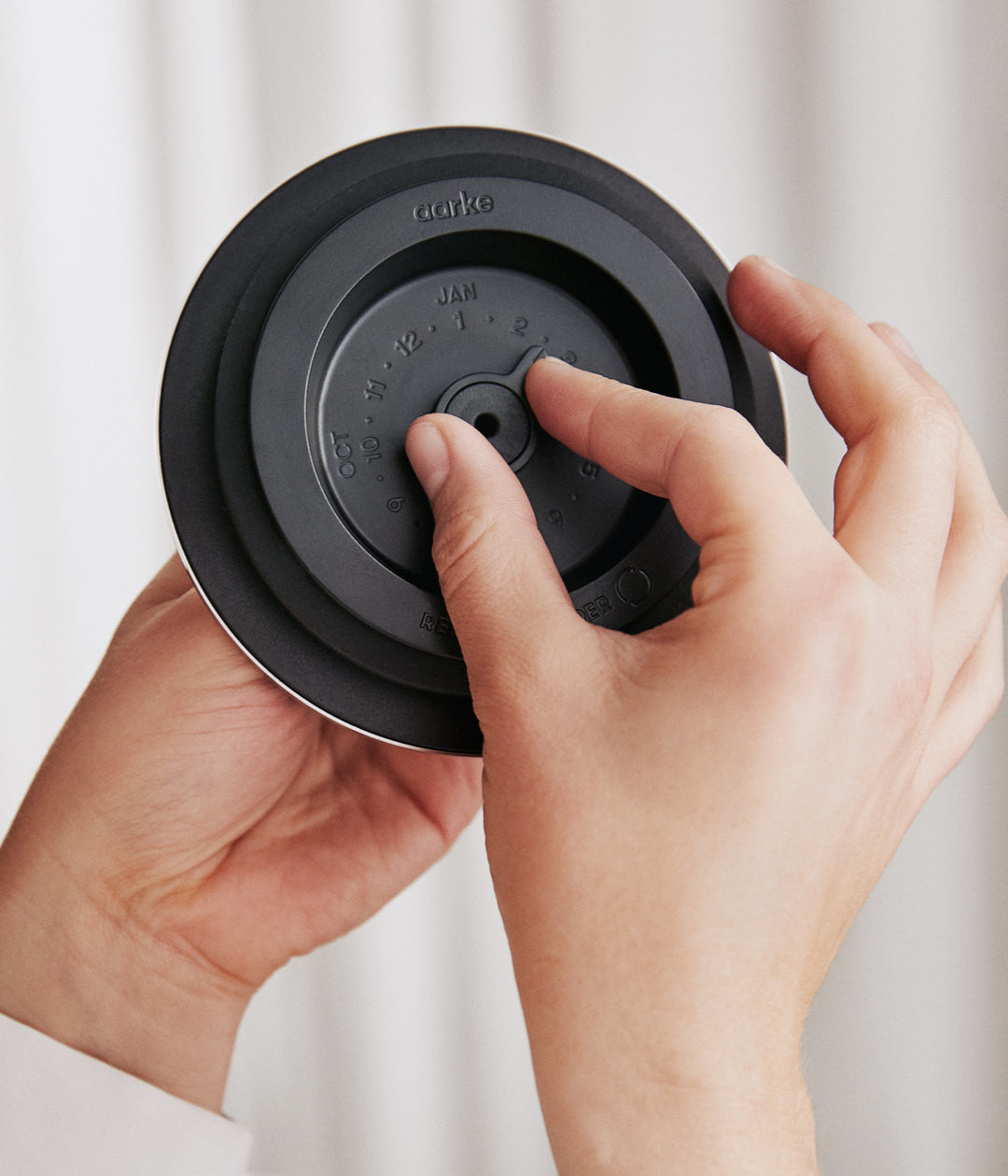 Dłonie obracające czarną, okrągłą tarczę z datami.
