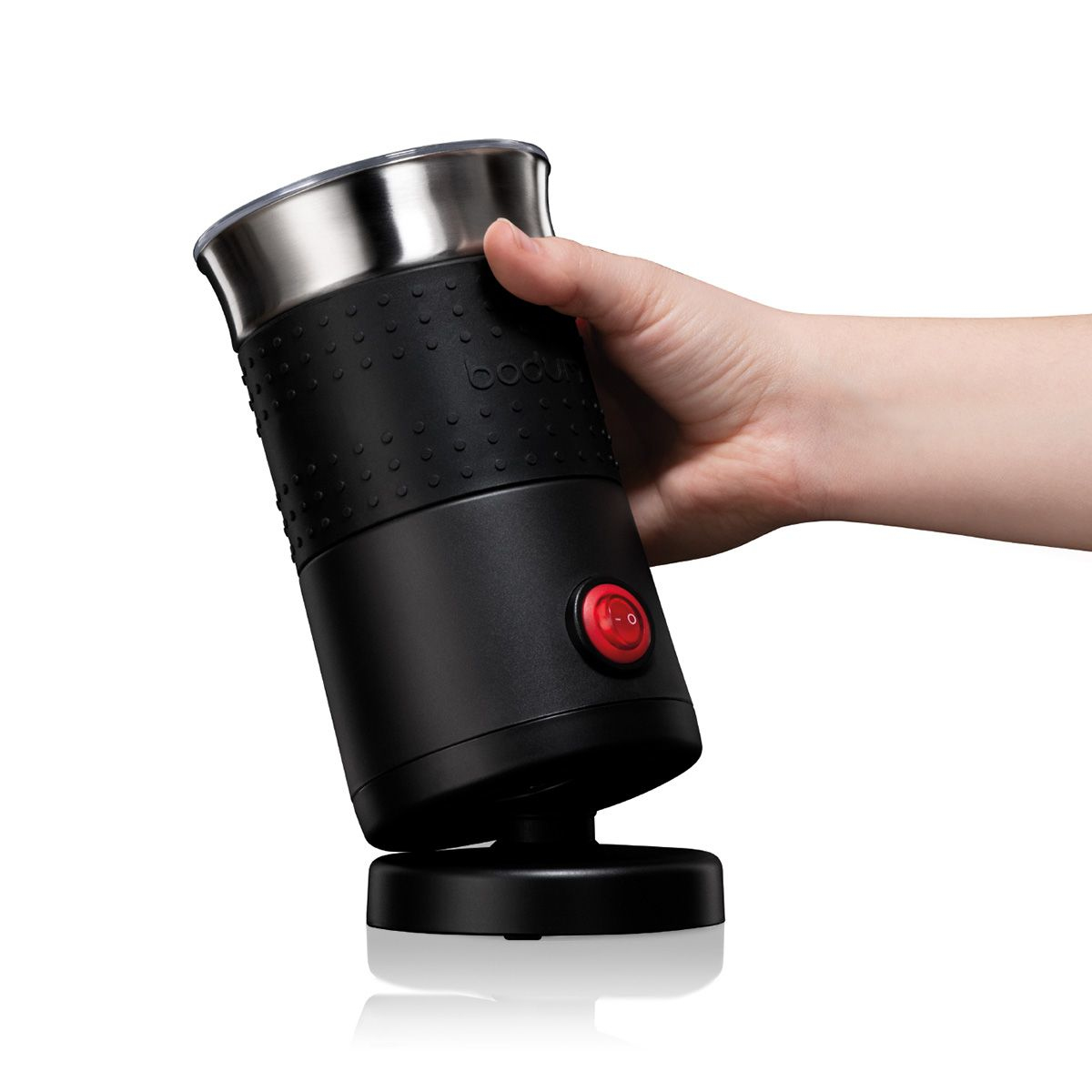 Czarno-srebrny spieniacz do mleka, trzymany przez dłoń, białe tło.