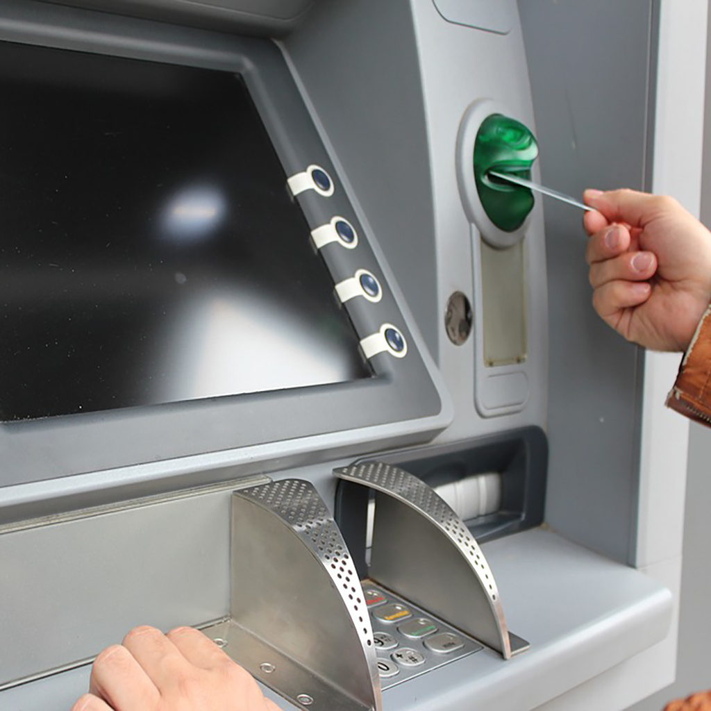 Osoba wkładająca kartę do bankomatu. Ekran jest widoczny.