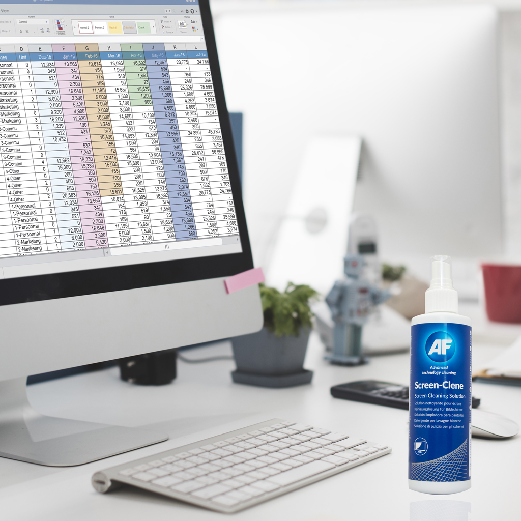 Biurko z komputerem, klawiaturą i butelką środka do czyszczenia ekranu. Pokazuje arkusz kalkulacyjny na ekranie.