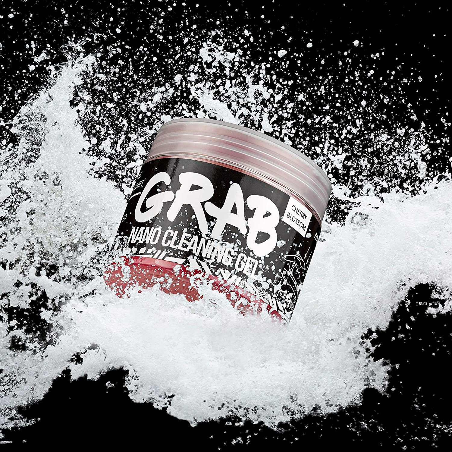 Un barattolo di gel detergente Nano Grab in uno splash d'acqua. L'etichetta è nera con testo bianco e un disegno.