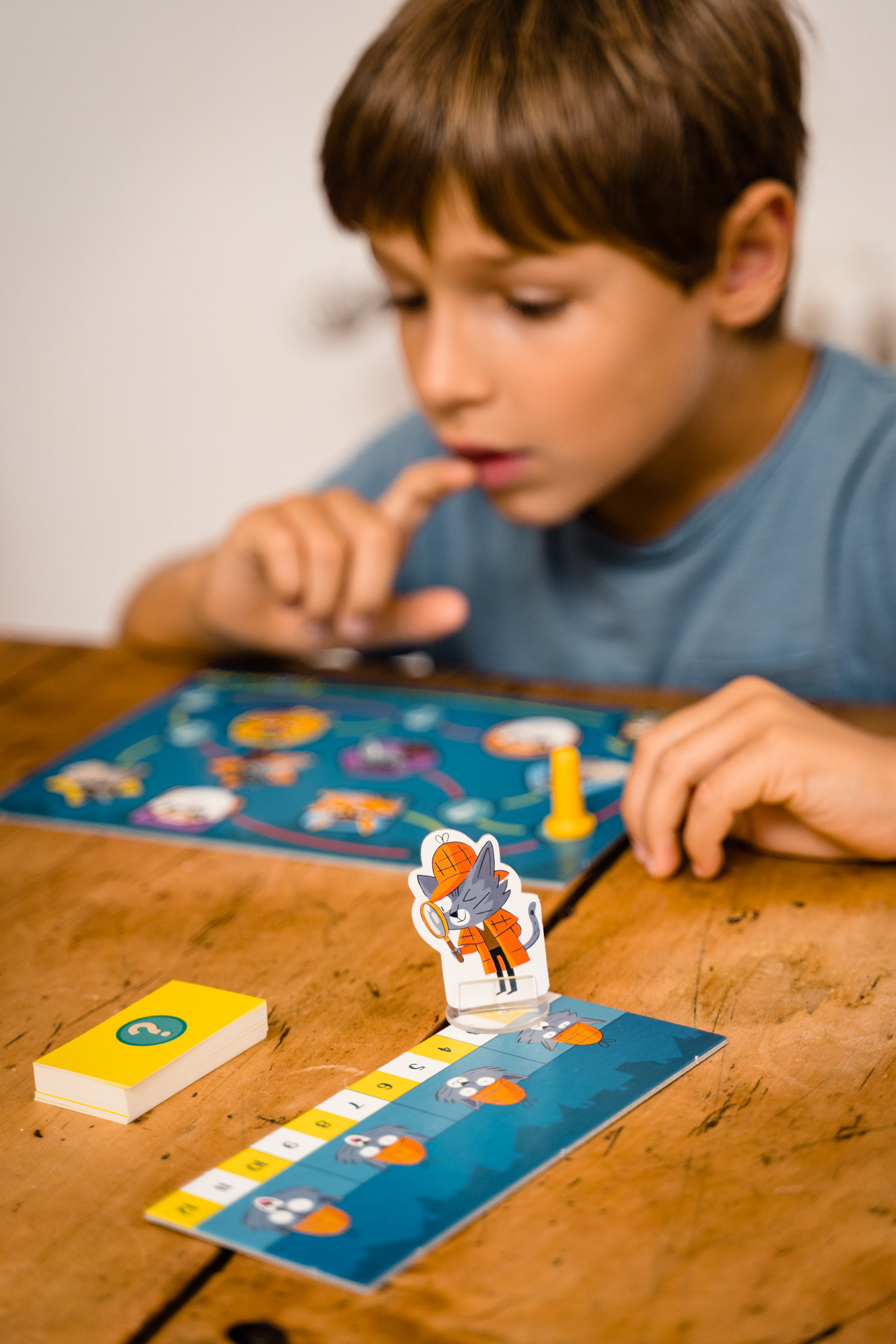 Ein Kind spielt ein Brettspiel an einem Holztisch.