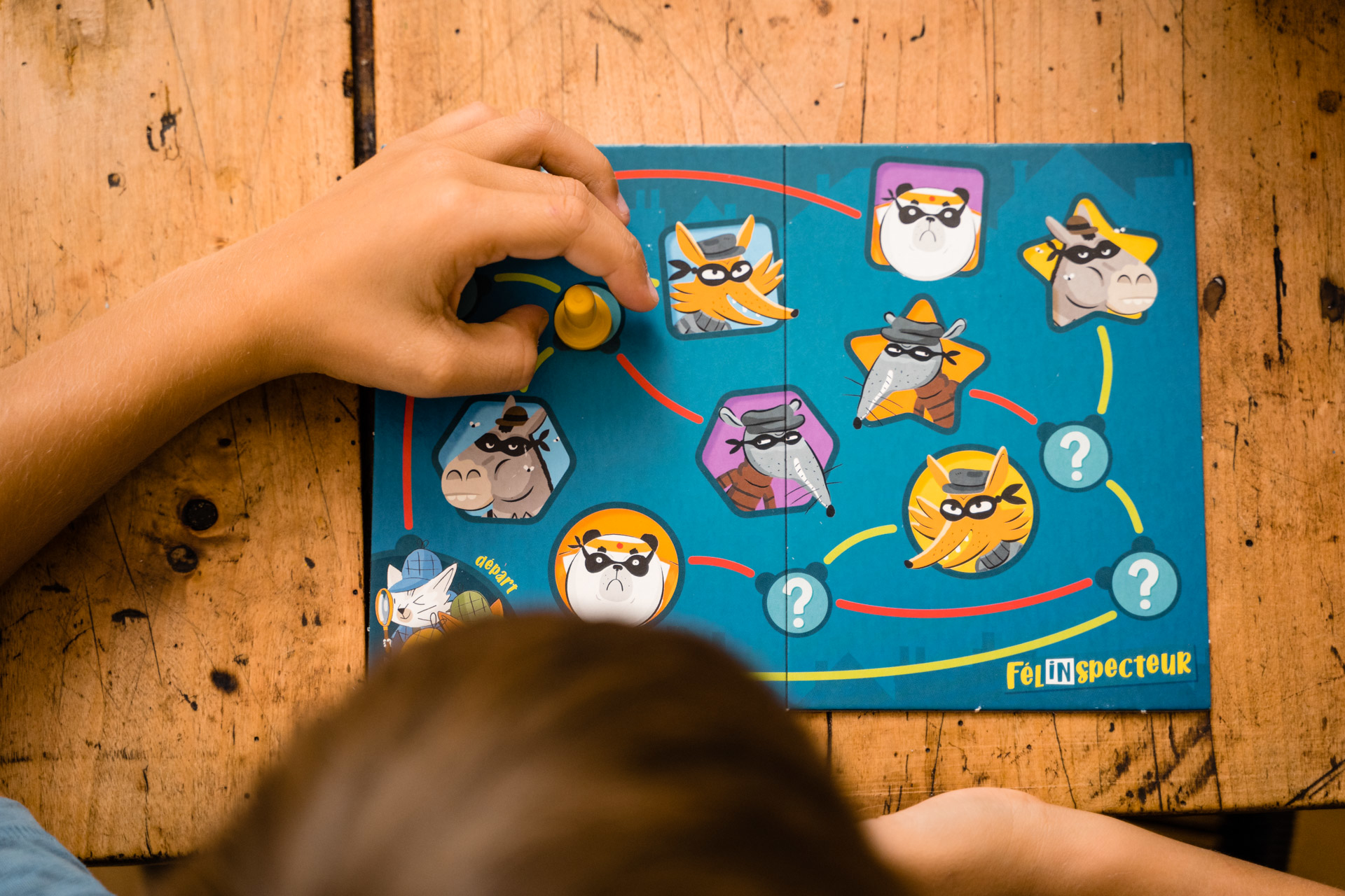 Die Hand eines Kindes interagiert mit einem Puzzlespiel mit Zeichentiergesichtern und blauem Hintergrund.