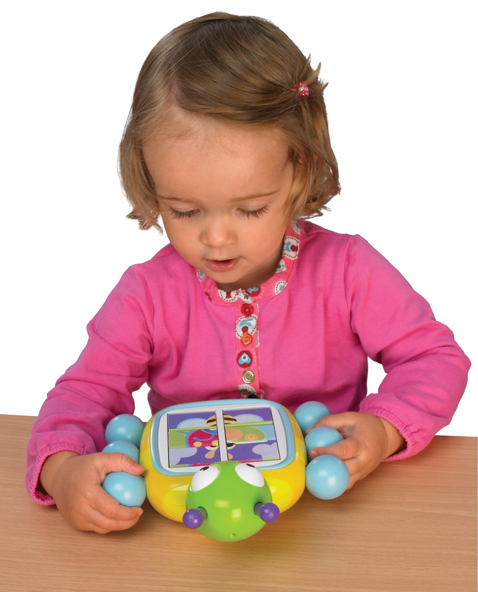 Mała dziewczynka bawiąca się kolorową zabawką na stole.