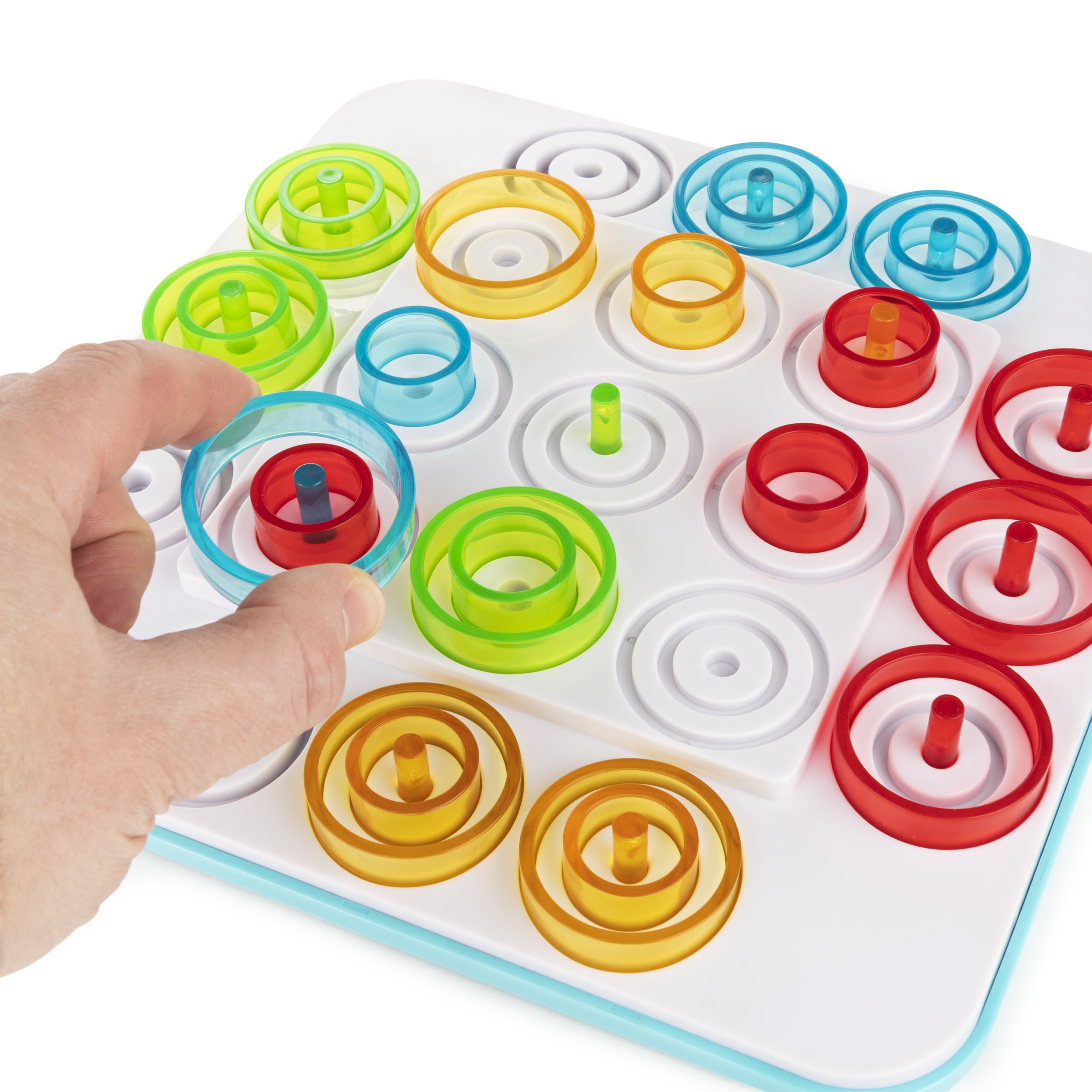 Eine Hand, die einen roten Ring auf ein weißes Brett mit bunten Ringen legt. Ein Ringstapelspiel.