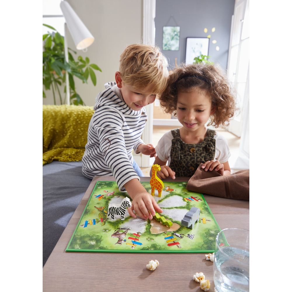Zwei Kinder spielen ein Brettspiel mit Tierfiguren auf einem Tisch.