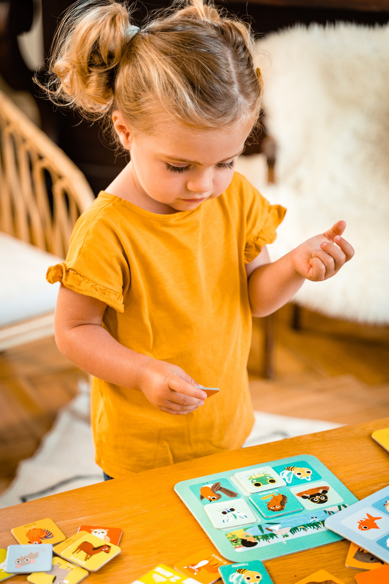 Mała dziewczynka z blond włosami bawiąca się kartami do gry w dopasowywanie.
