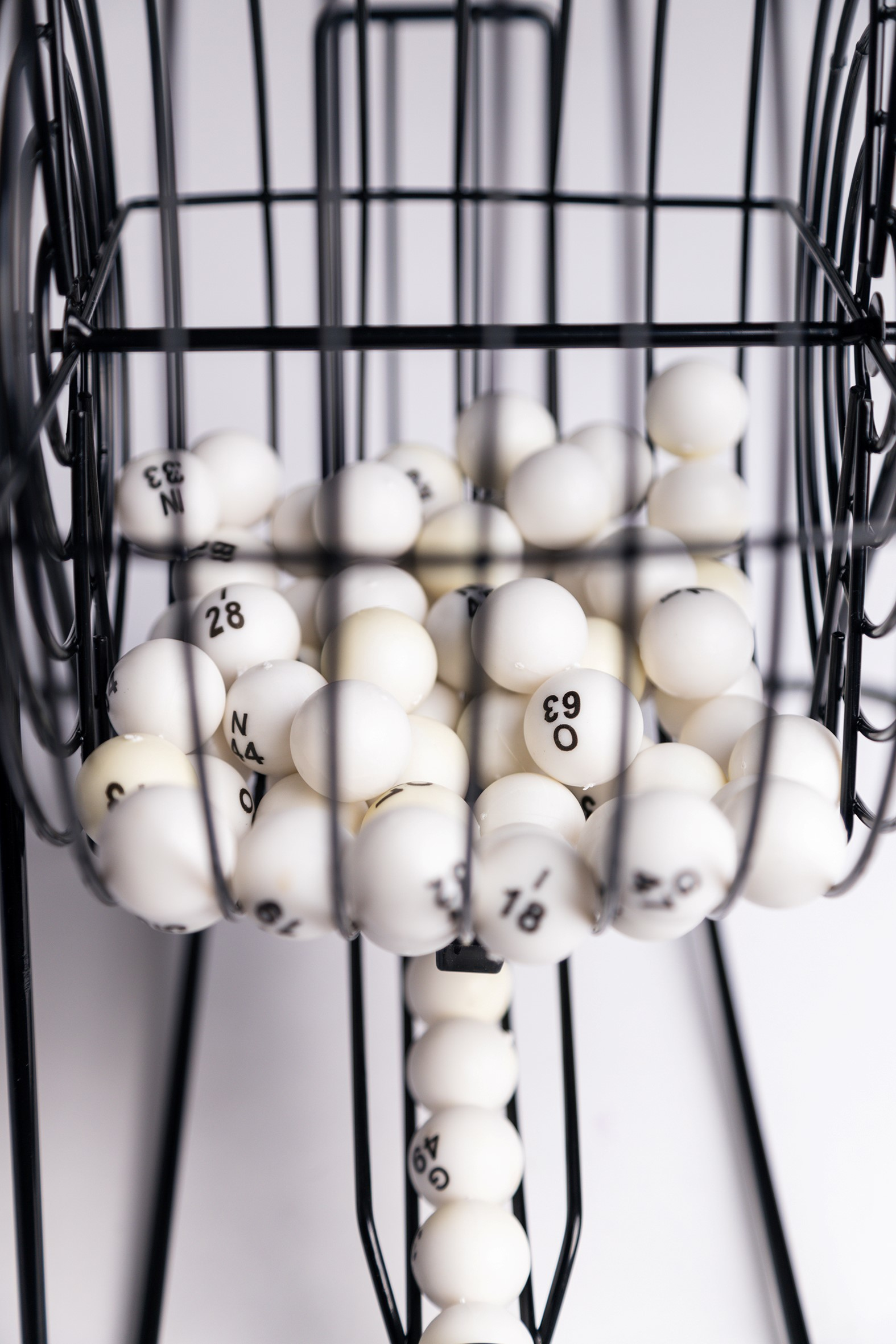 Un primo piano di una gabbia di bingo piena di palline bianche, alcune con numeri visibili.