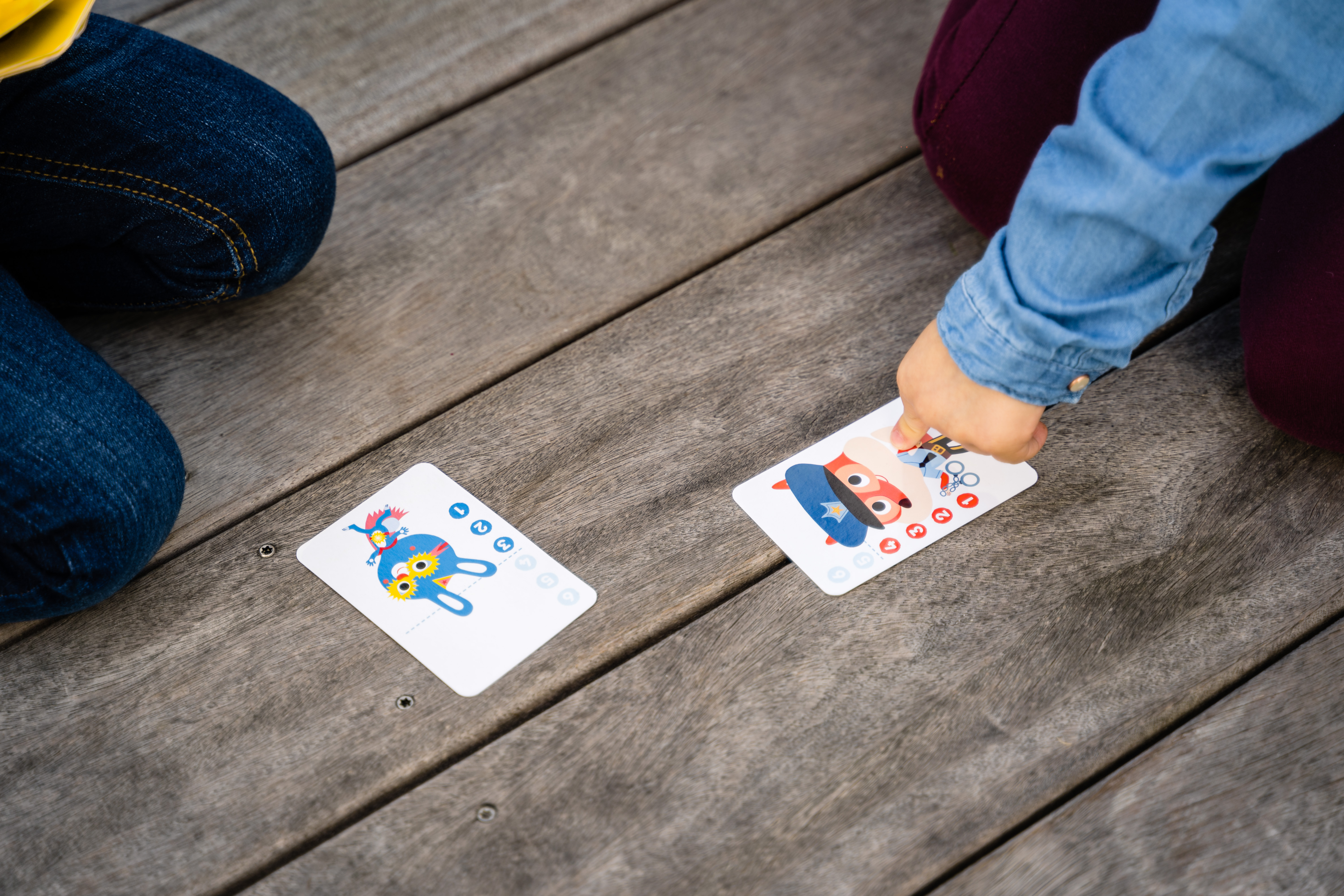 Due bambini giocano a carte su una superficie di legno. I bambini sono in un parco o all'aperto.