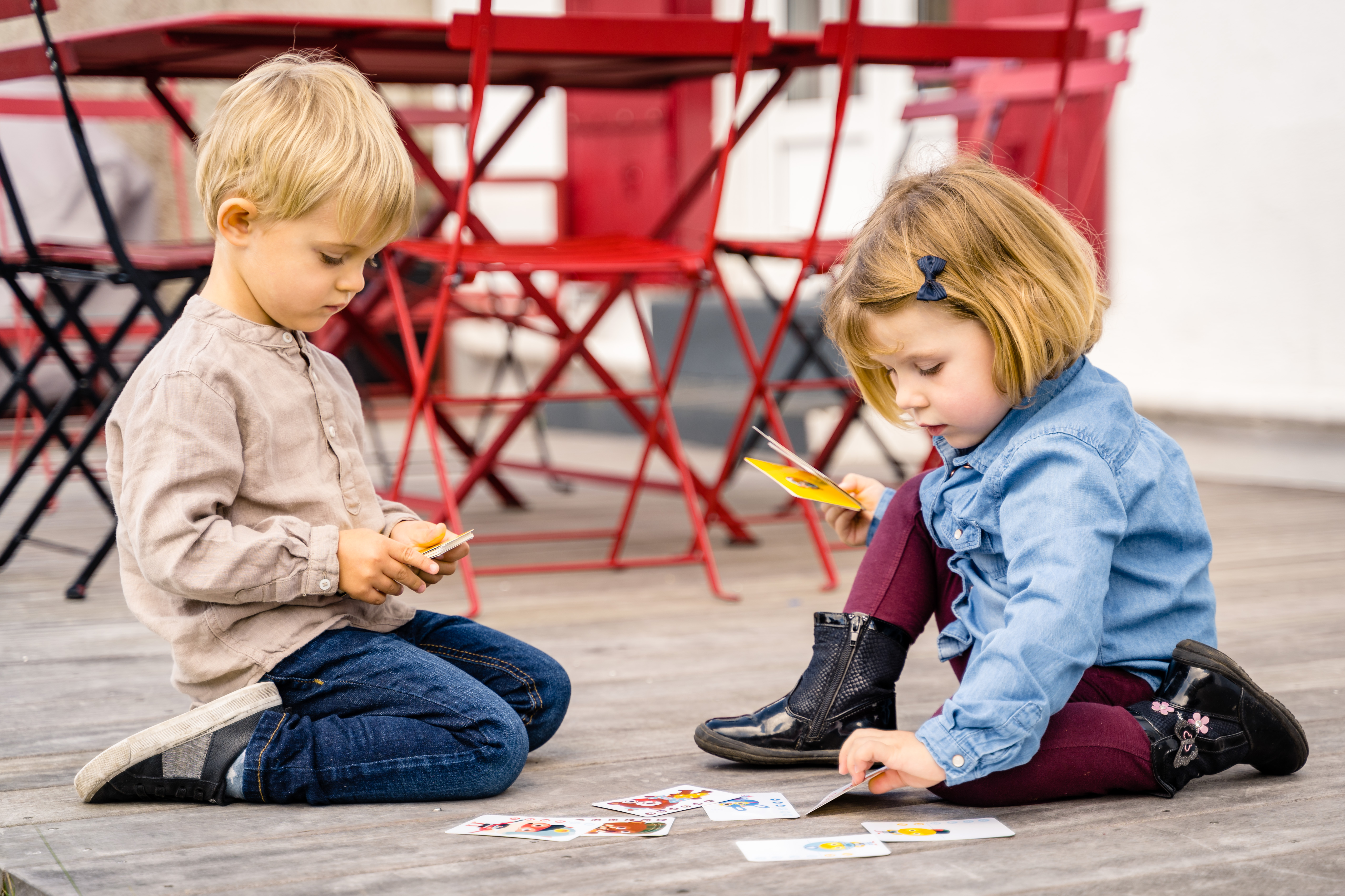 Due bambini giocano a carte su una superficie di legno. I bambini sono in un parco o all'aperto.