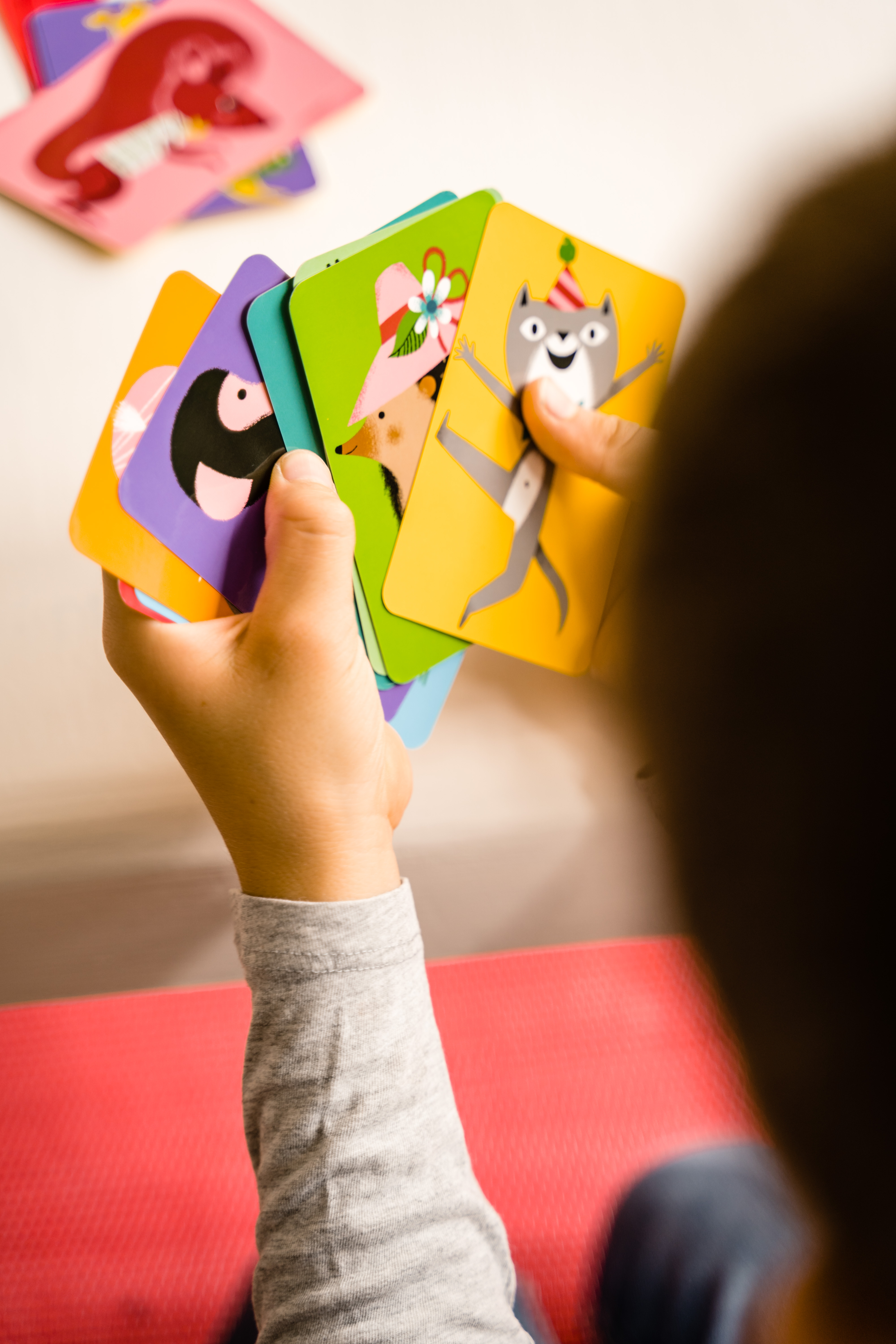Osoba trzymająca wachlarz kolorowych kart z ilustracjami zwierząt.