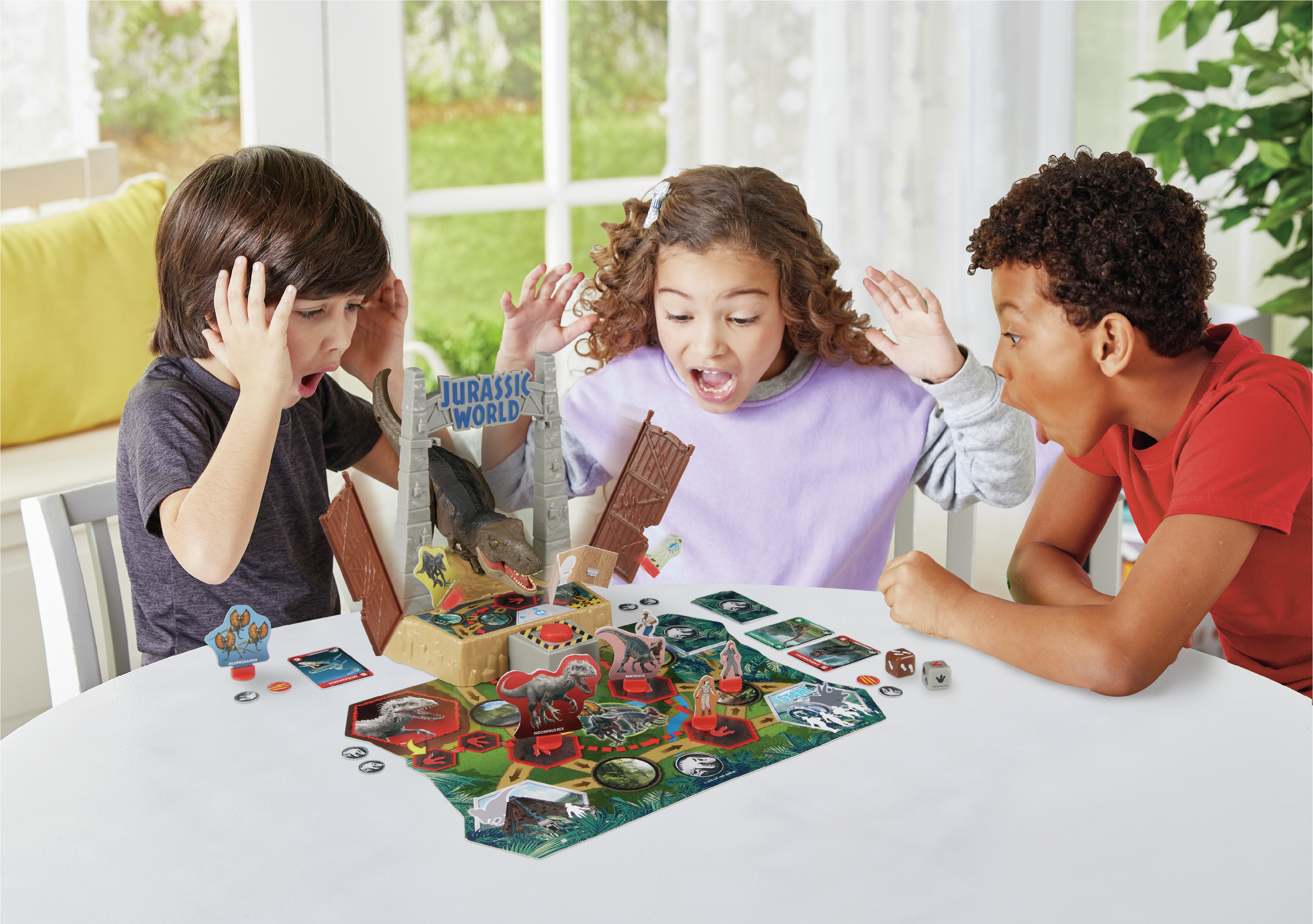 Tre bambini giocano a un gioco da tavolo di Jurassic World. Hanno espressioni sorprese.