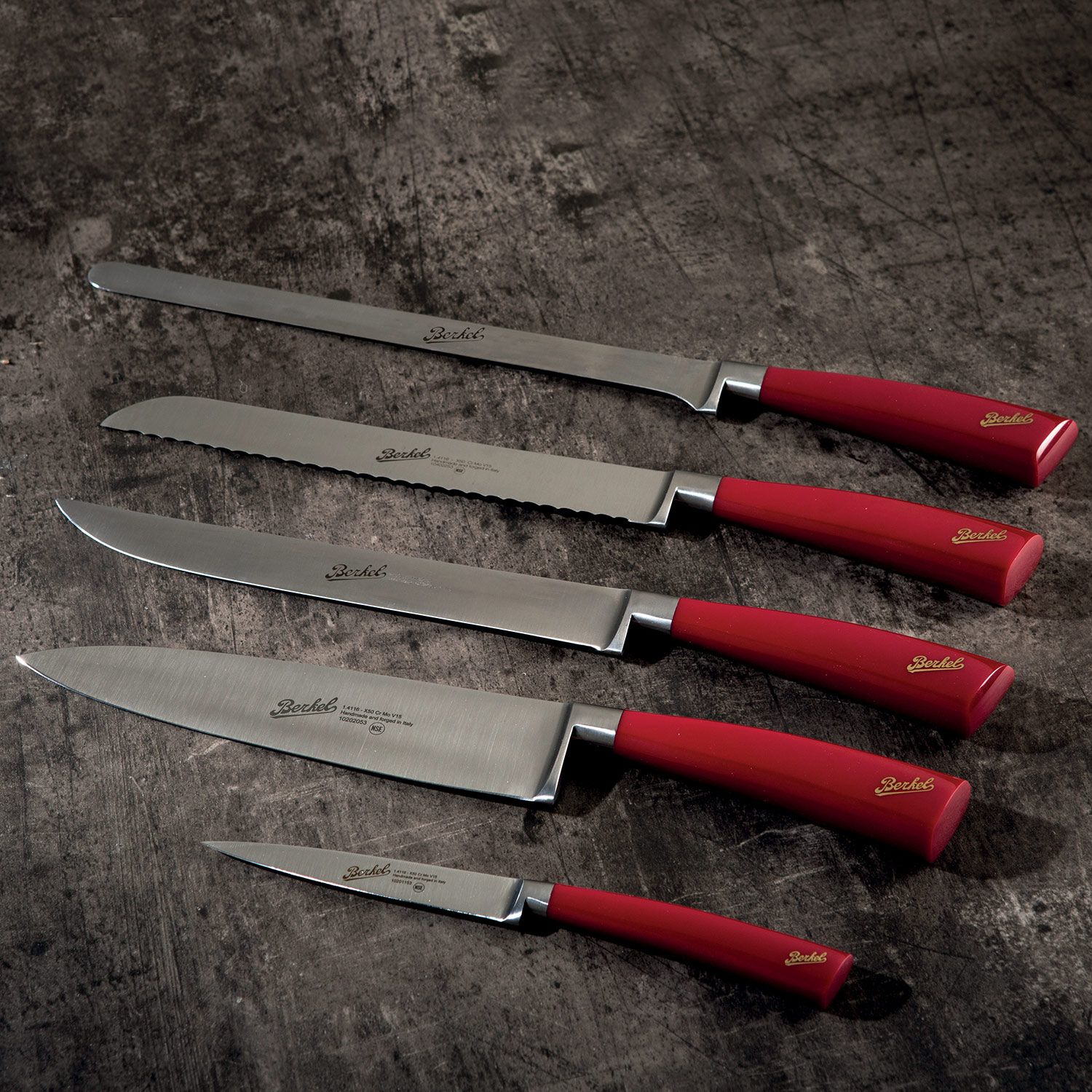 Cztery noże z czerwonymi uchwytami na teksturowanej szarej powierzchni. Noże różnią się kształtem i rozmiarem.