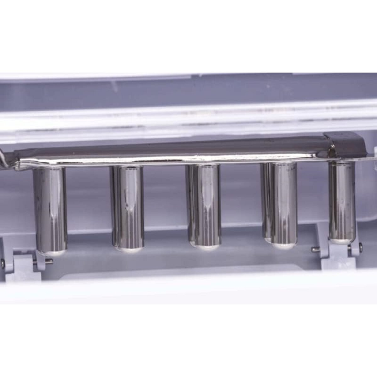 Binnenkant van een ijsmachine. Metalen staven en een witte plastic basis zijn zichtbaar.