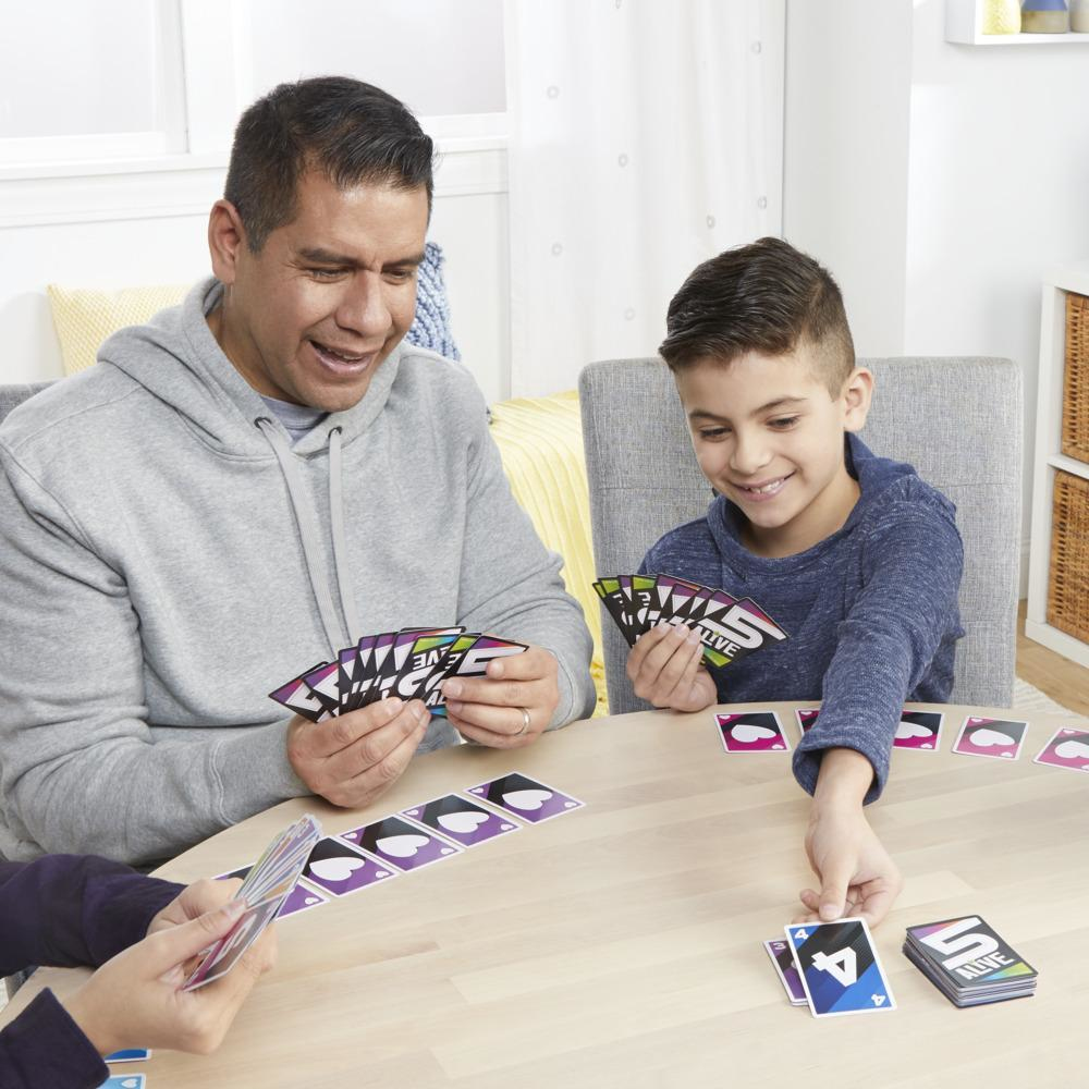 Twee volwassenen en een kind spelen een kaartspel aan een tafel.