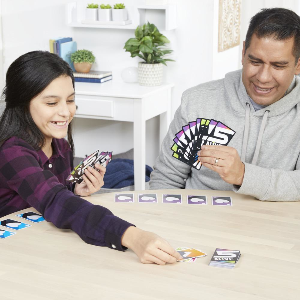 Een gezin speelt het 5 Alive kaartspel. Kaarten zijn zichtbaar op tafel. Het gezin lacht en is betrokken.