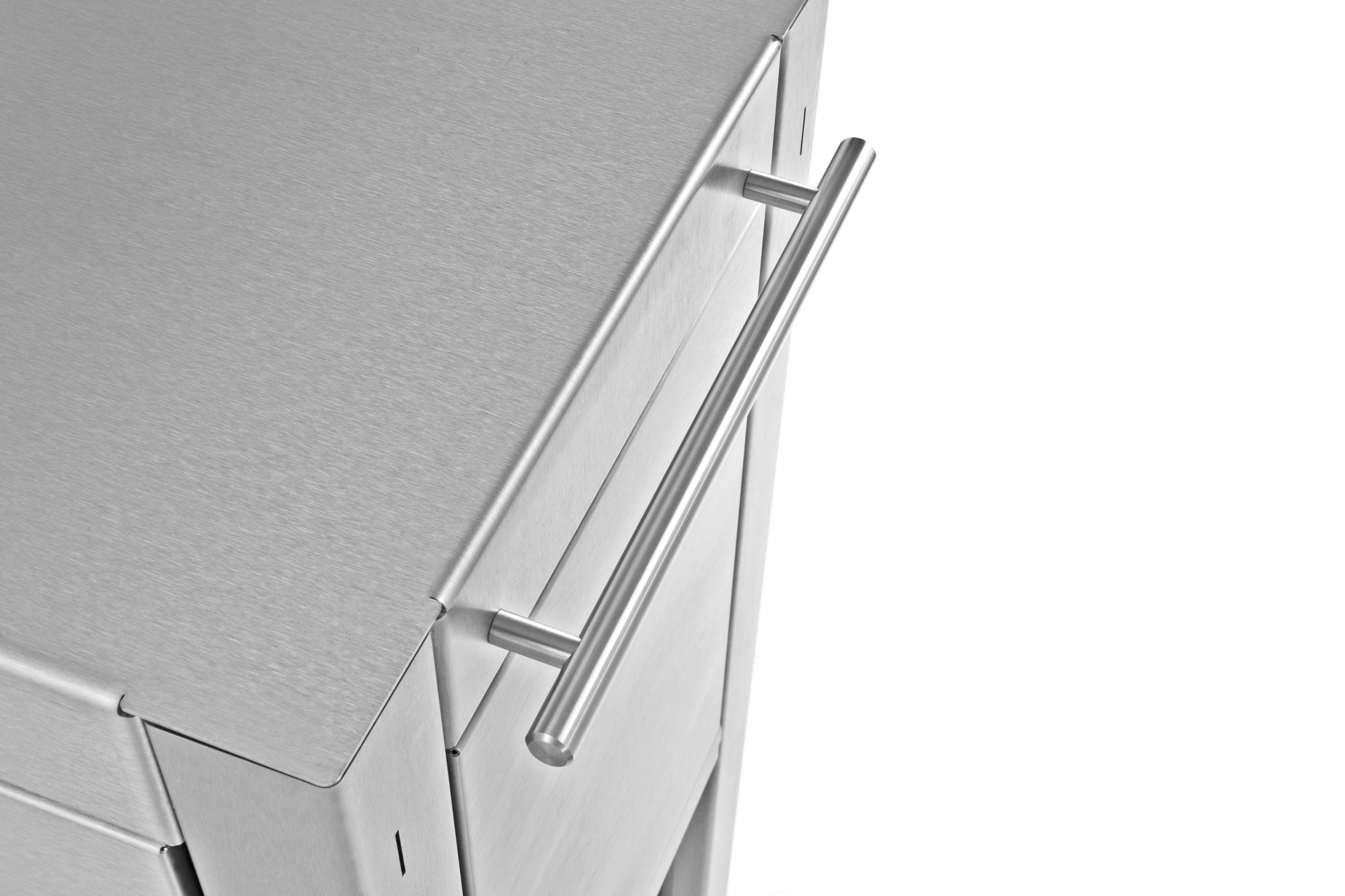 Szczegół wózka kuchennego ze stali nierdzewnej. Pokazuje uchwyt oraz fragment górnego i bocznego panelu.