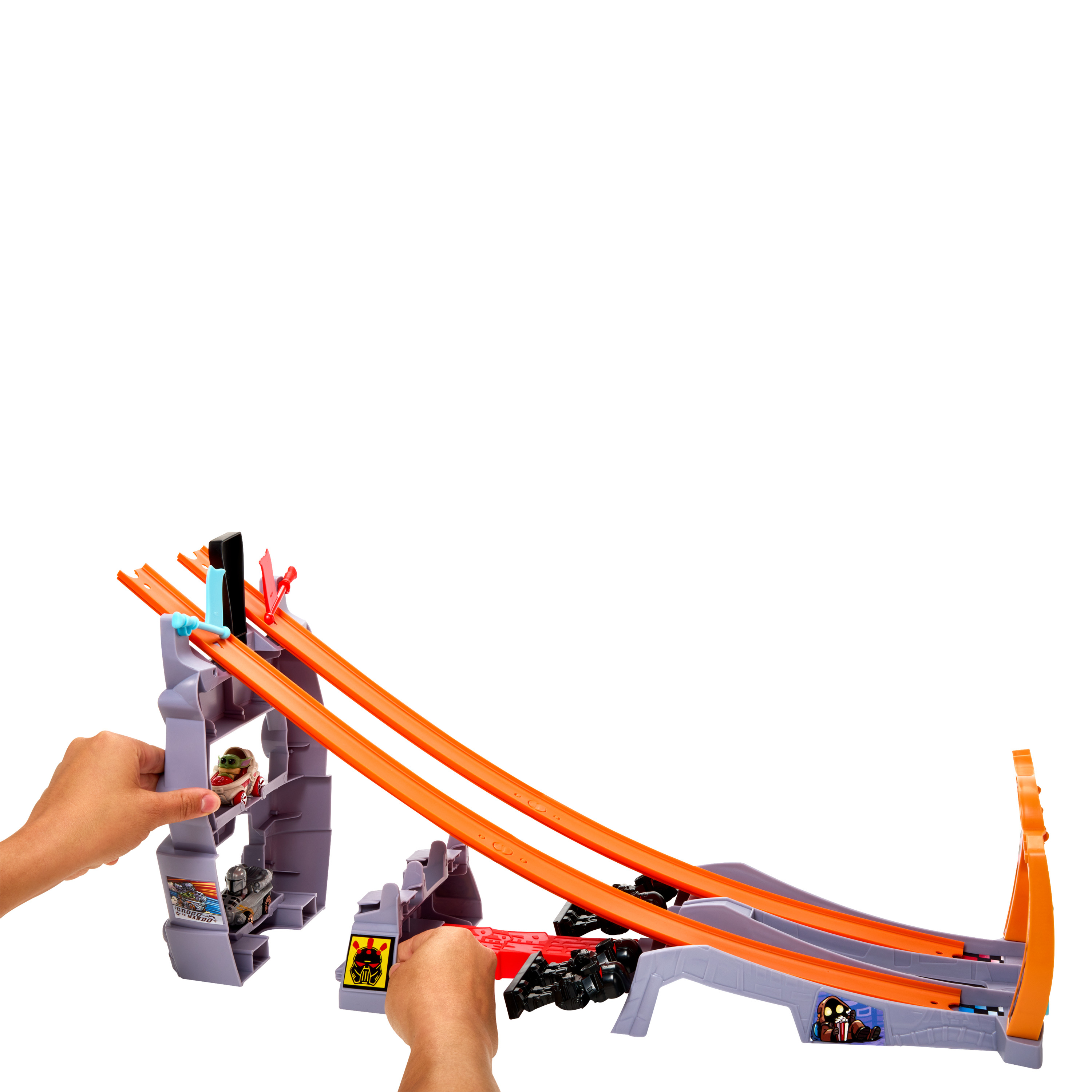 Eine Hot Wheels-Bahn mit Spielzeugautos und Händen, die Autos die orangefarbene Strecke hinunterstarten.