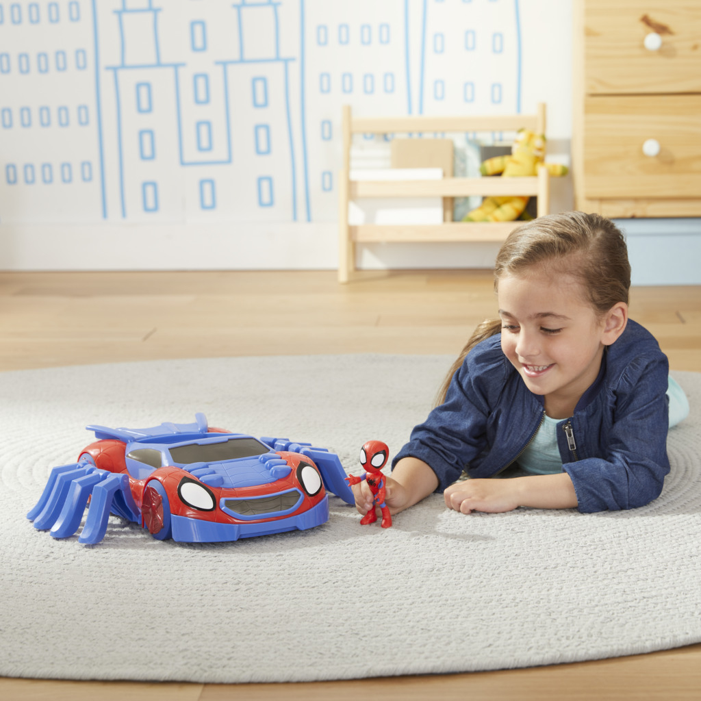 Dziewczynka bawi się zabawką Spider-Mana i figurką na szarej macie.