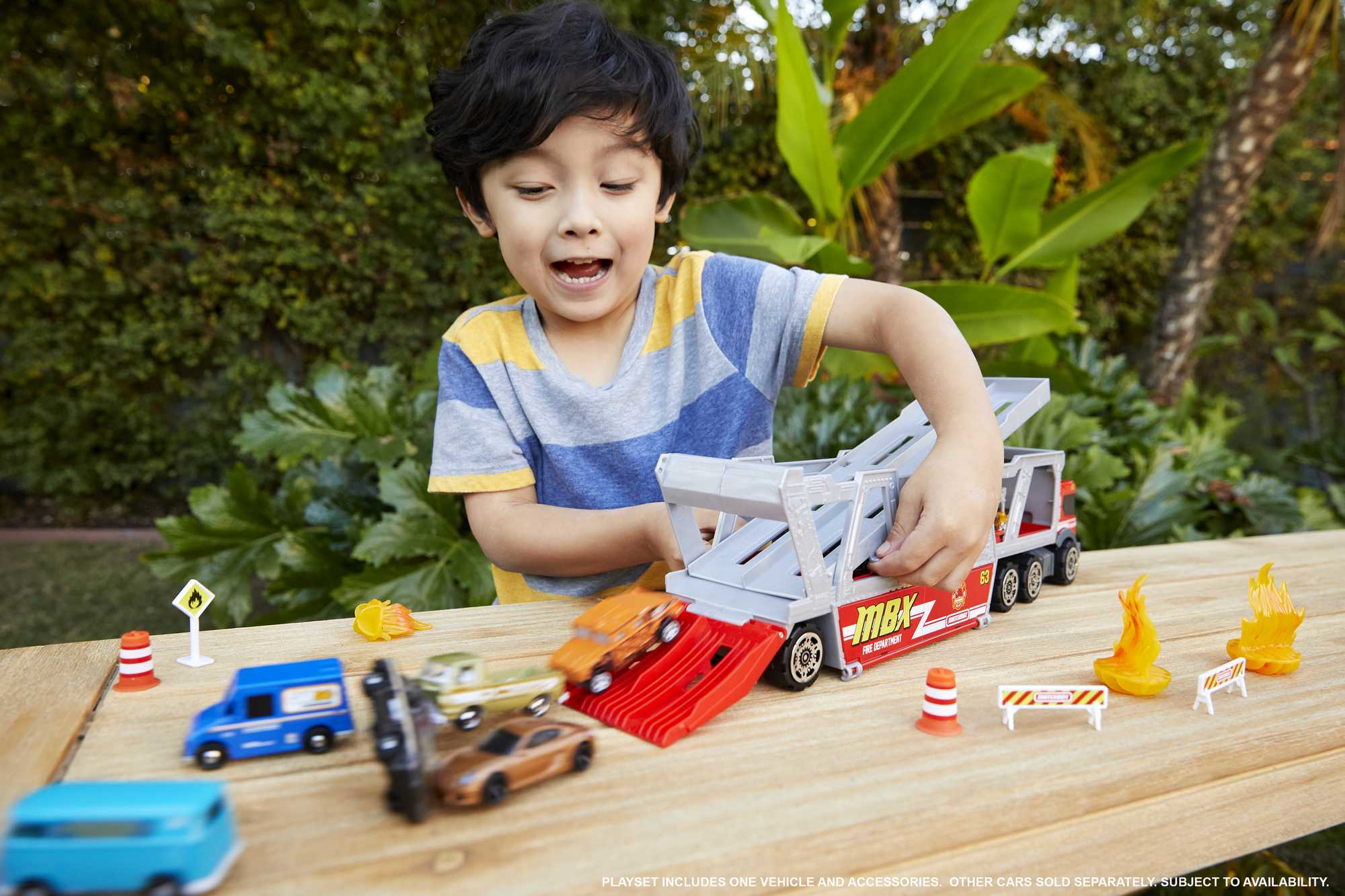 Ein Kind spielt mit einem Spielzeug-Feuerwehr-Set, einschließlich Zubehör und kleineren Spielzeugautos.
