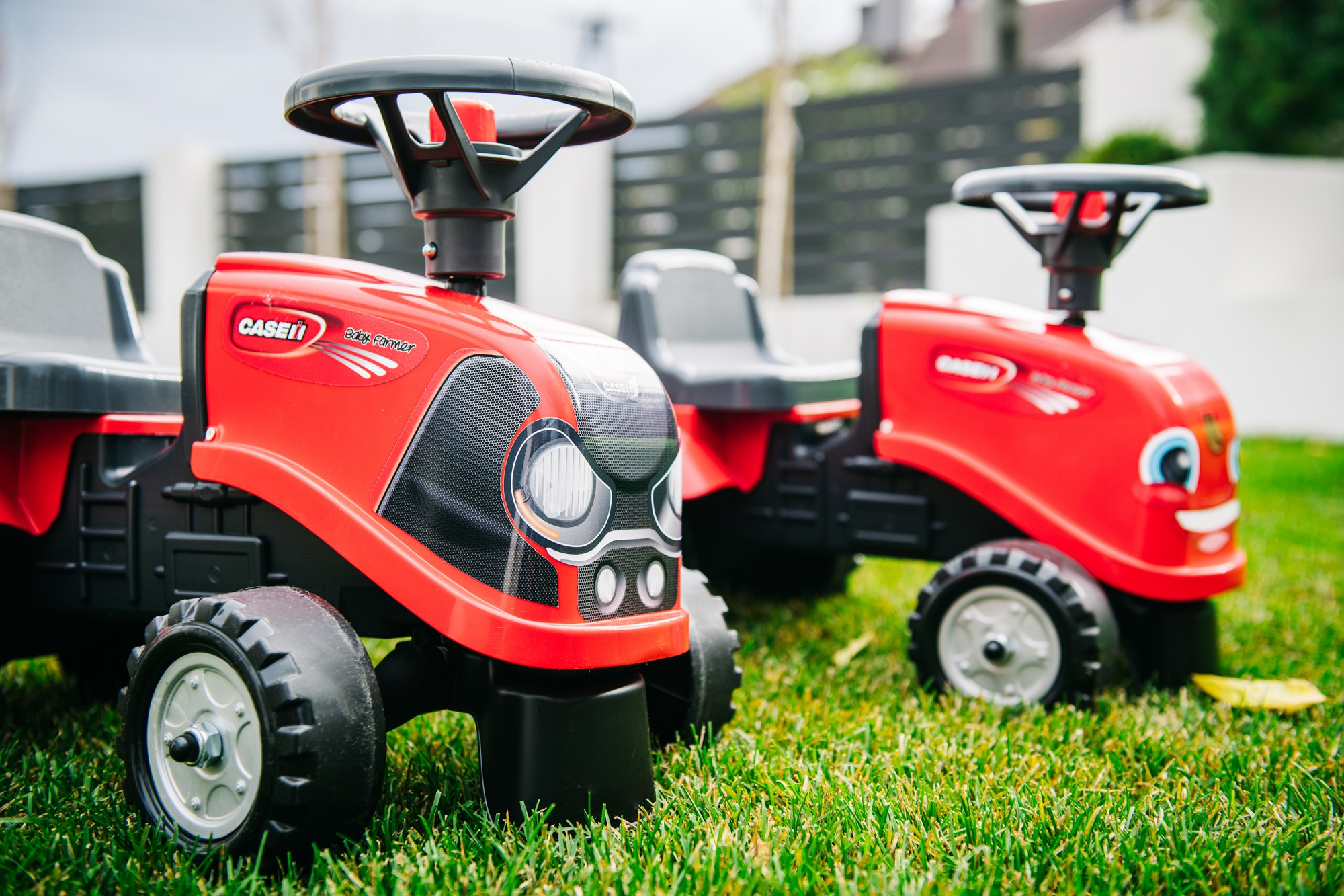 Dos juguetes de tractor Case rojos sobre hierba verde. El enfoque está en el más cercano.