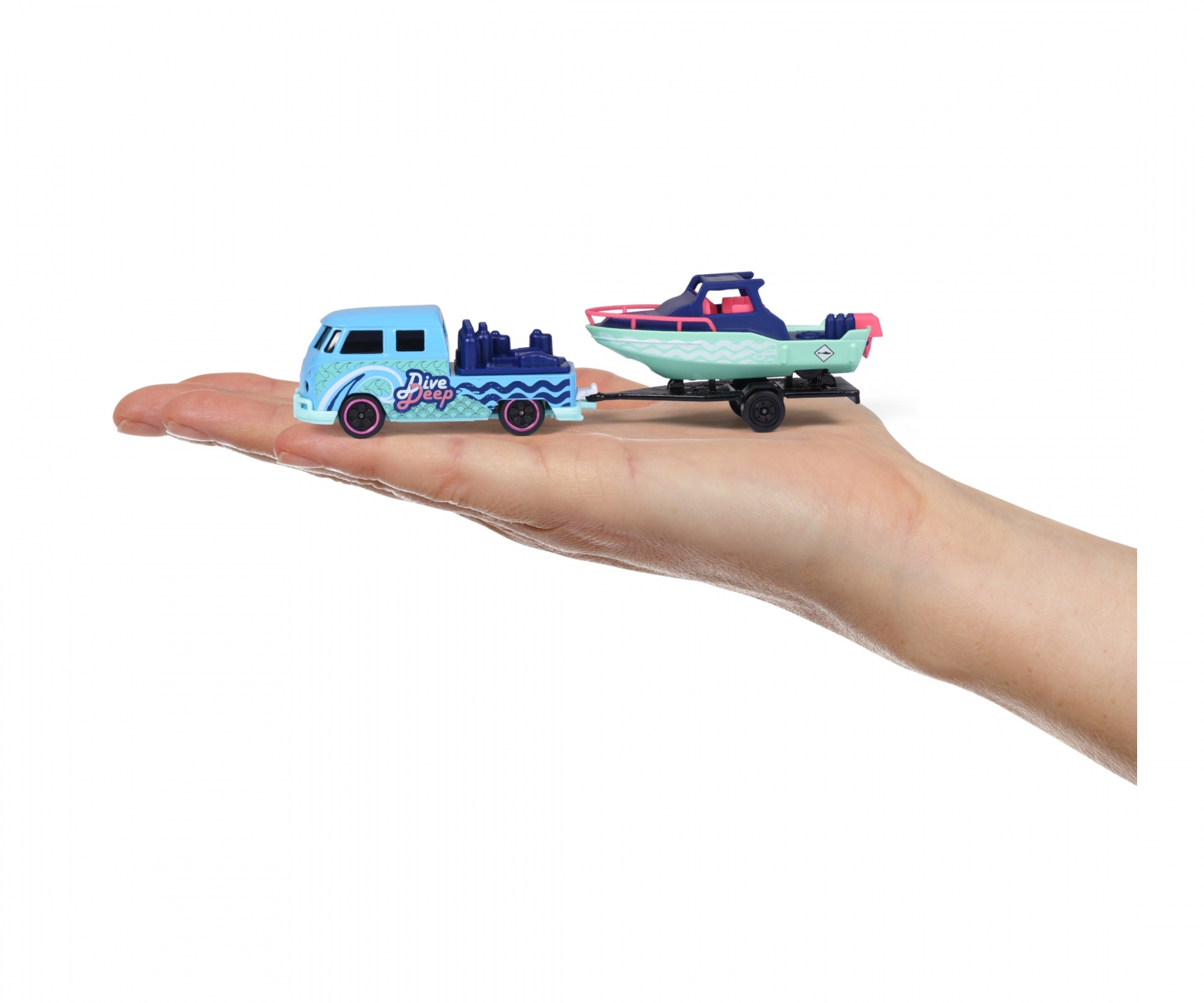 Dłoń trzymająca zabawkę ciężarówkę holującą łódź. Ciężarówka jest niebieska, a łódź turkusowa i różowa.
