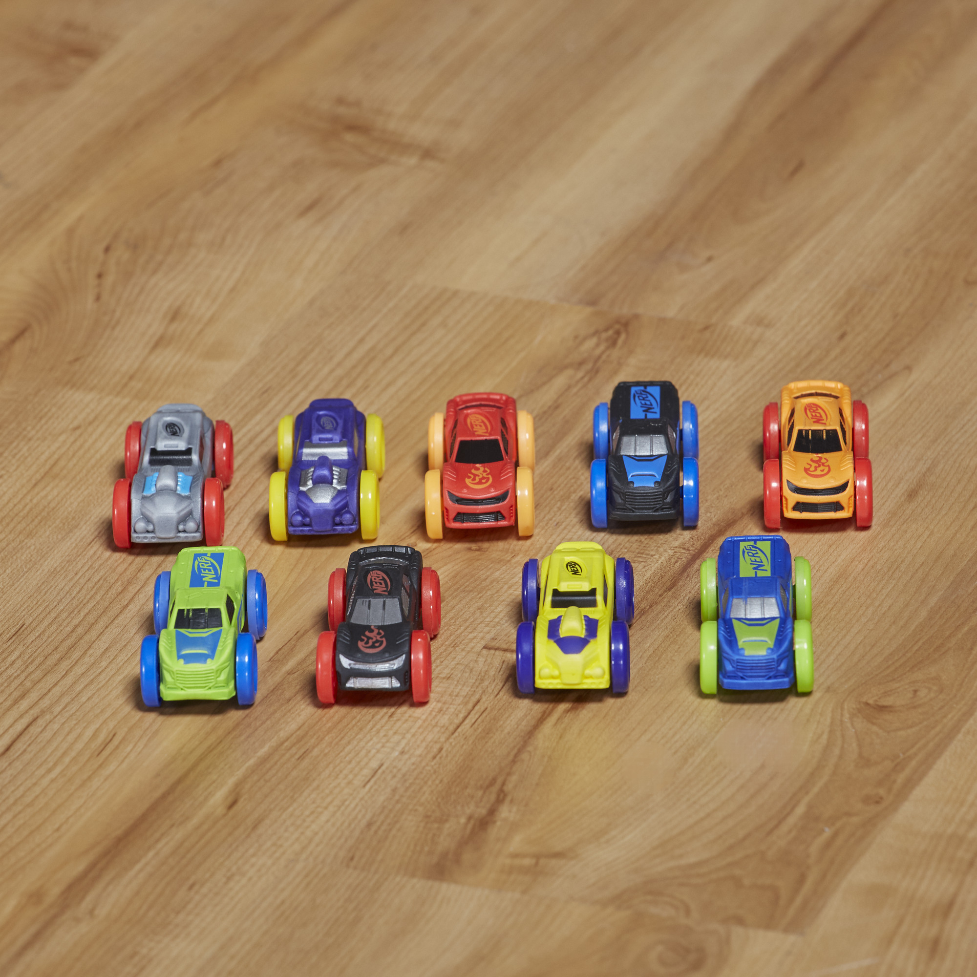 Dziewięć kolorowych zabawek samochodowych na drewnie. Każdy samochód ma inny kolor.