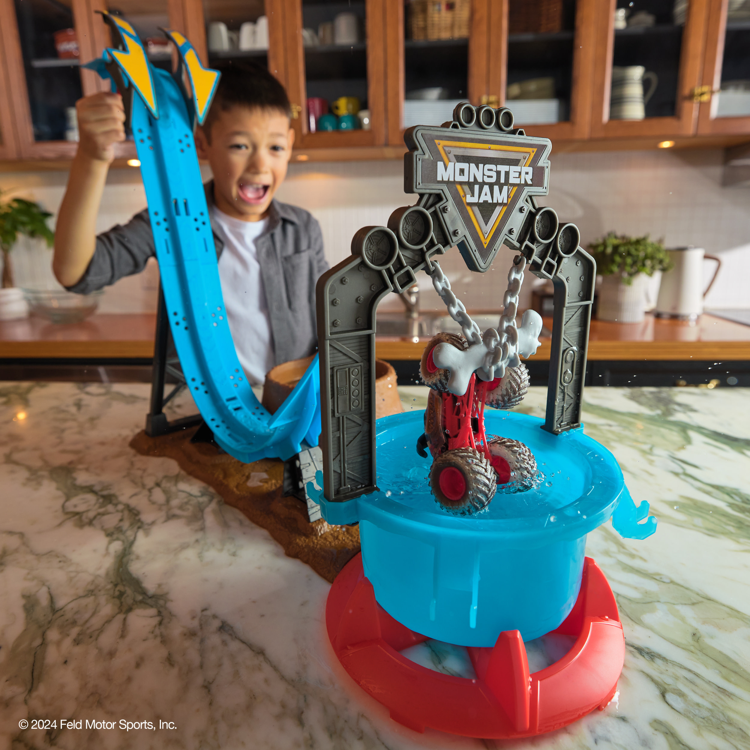 Un niño juega con un juego de juguetes Monster Jam, con una rampa y un camión en agua.