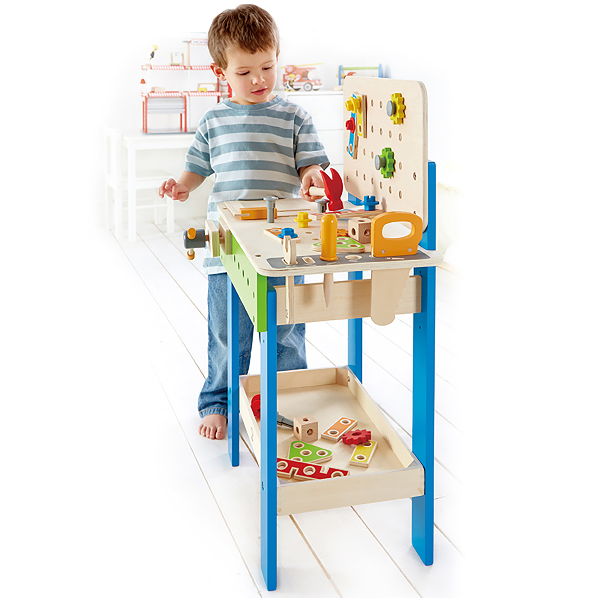 Chłopiec przy drewnianym warsztacie z narzędziami. Chłopiec ma na sobie koszulę i dżinsy. Tło jest białe.