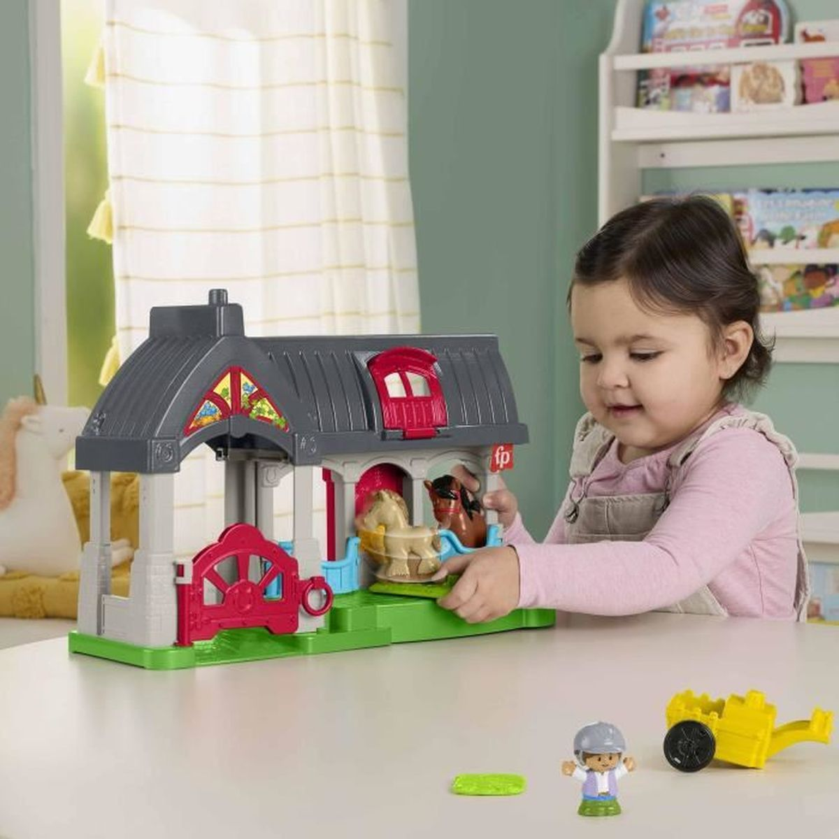 Una bambina che gioca con un set di fattoria giocattolo. Il set ha un fienile, animali e accessori. Una mensola sullo sfondo.