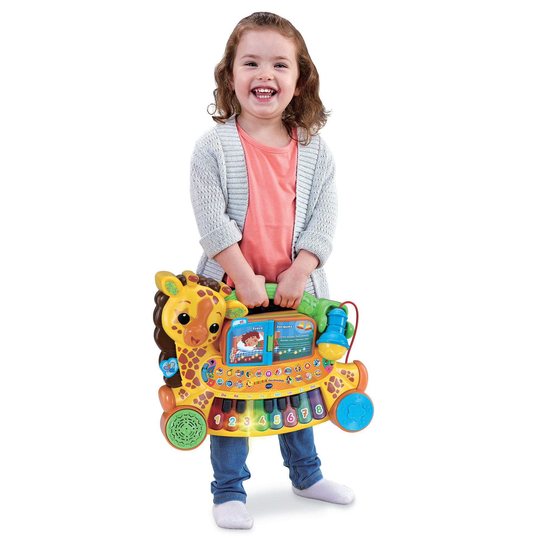 Una niña pequeña sosteniendo un teclado de juguete colorido con forma de jirafa, sonriendo, con un fondo blanco.