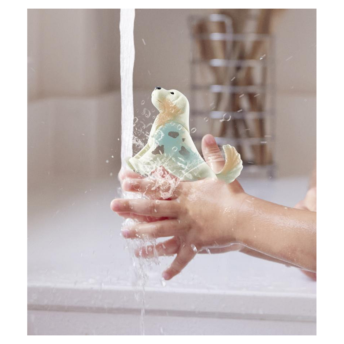 Een kind wast een speelgoedzeehond onder stromend water.