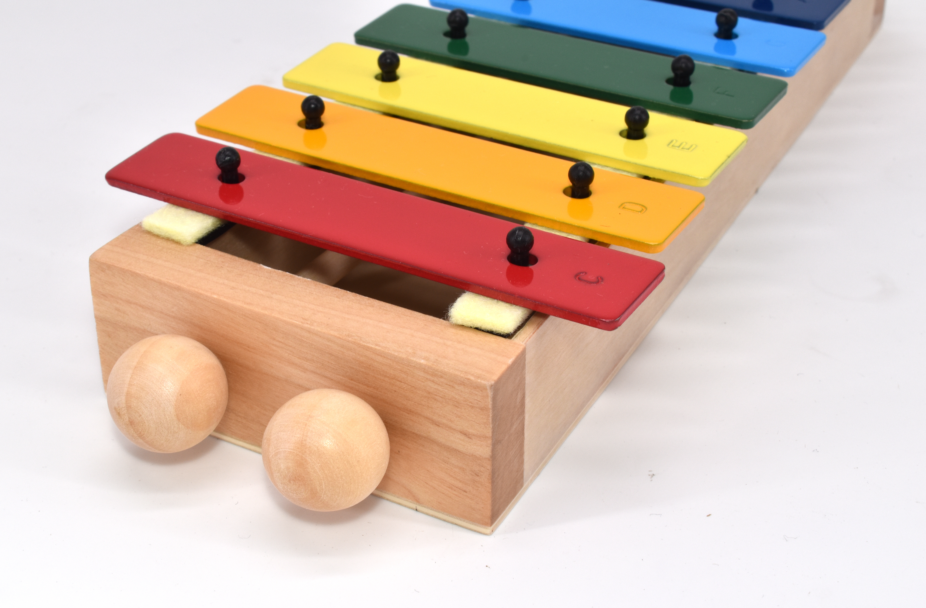 Holz-Xylophon mit farbigen Tasten. Rote, orange, gelbe, grüne, blaue Tasten. Zwei Holzschlägel. Weißer Hintergrund.