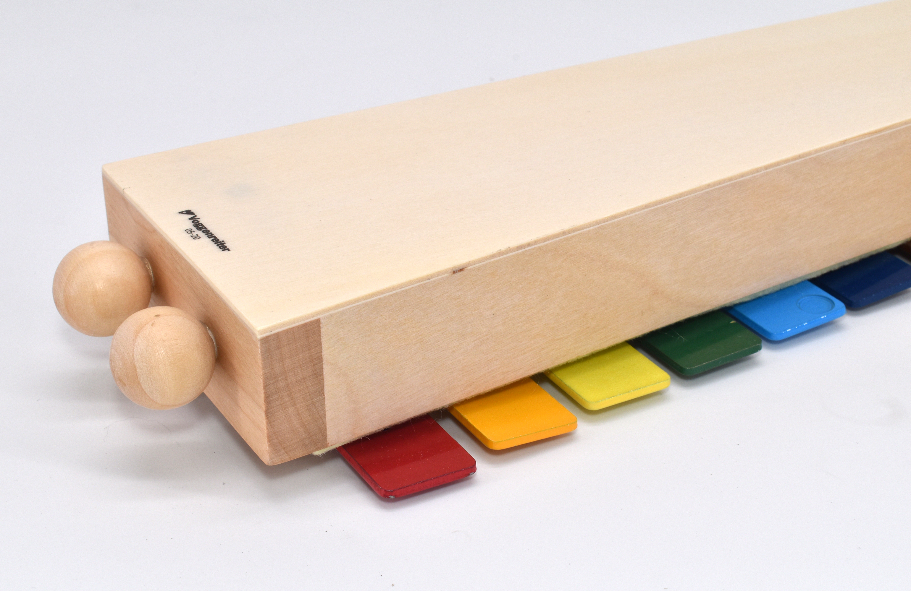 Ein hölzernes Spielzeuginstrument mit bunten Tasten und zwei Holzschlägeln. Weißer Hintergrund.