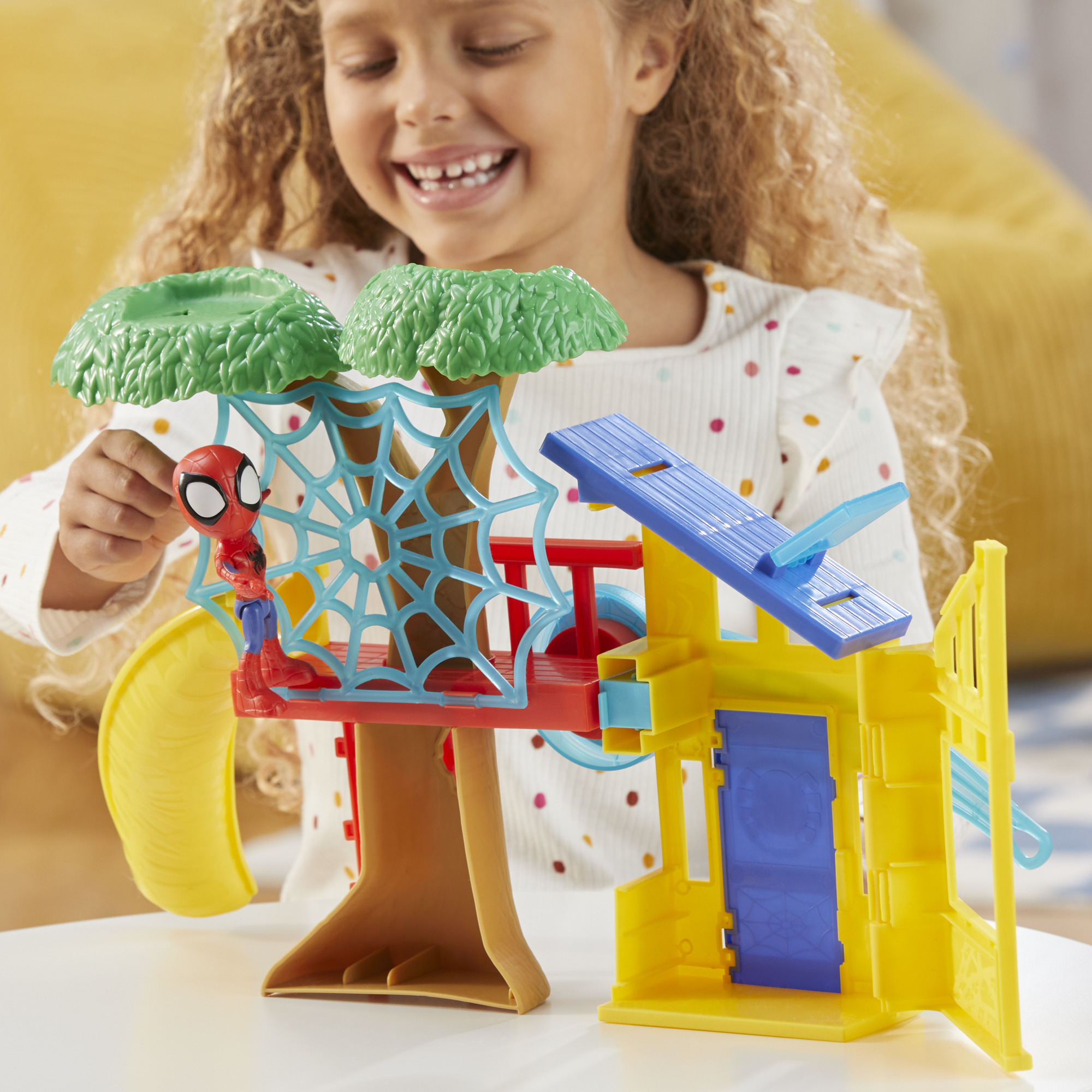 Una bambina gioca con un set di giocattoli di Spider-Man con una casa sull'albero, uno scivolo e la figura di Spider-Man.