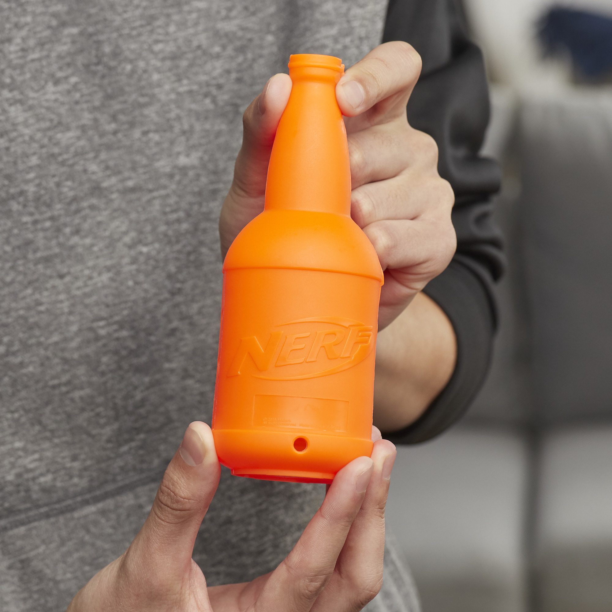 Persona sosteniendo una botella Nerf naranja con el logo de Nerf.
