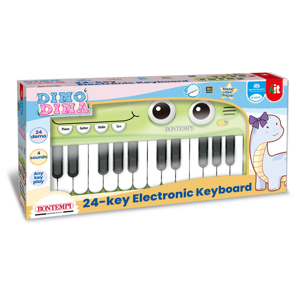 Ein grünes Spielzeugklavier in einer Schachtel mit Dinosaurier-Design. Weiße und schwarze Tasten. Weißer Hintergrund.