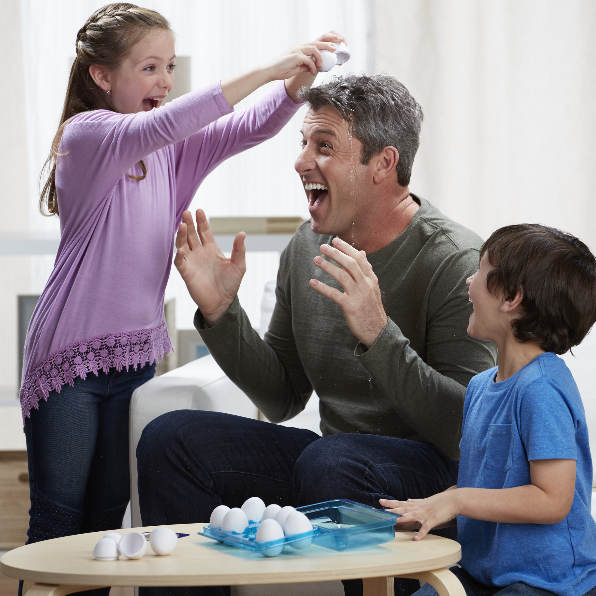 Famiglia che gioca a un gioco da tavolo in cui un bambino lancia un uovo al padre. Sfondo bianco.