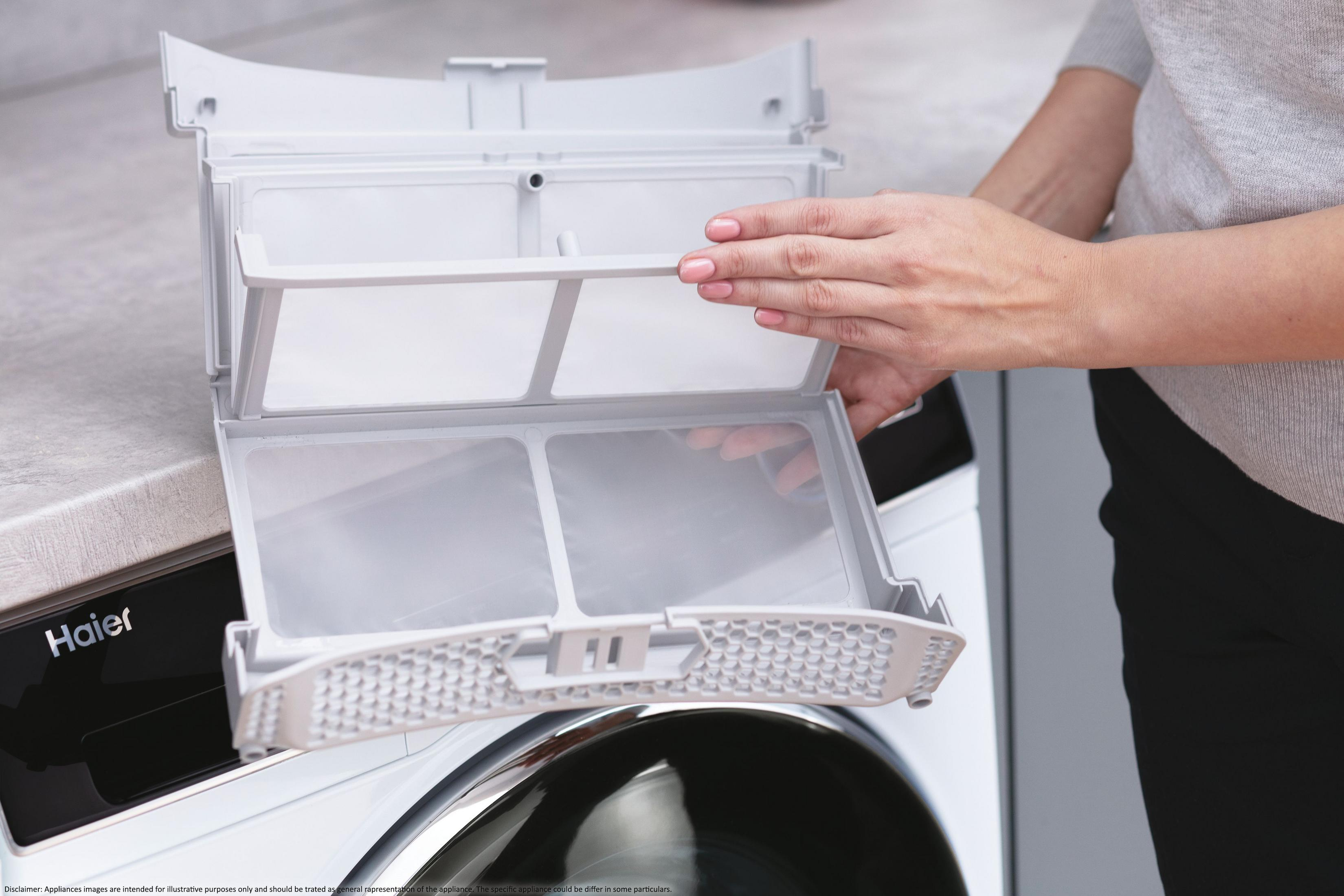 Hände einer Frau entfernen Filter aus einem Haier Trockner. Hintergrund ist eine Arbeitsplatte.