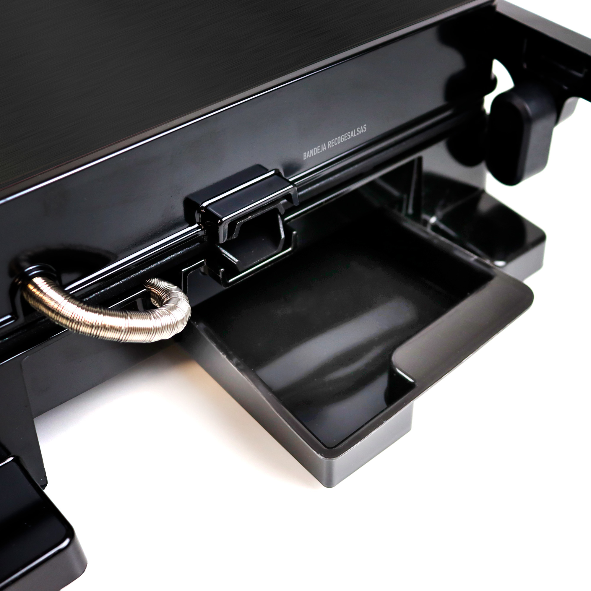 Szczegół czarnej tacy drukarki. Taca jest wyciągnięta. Srebrna rurka po lewej.