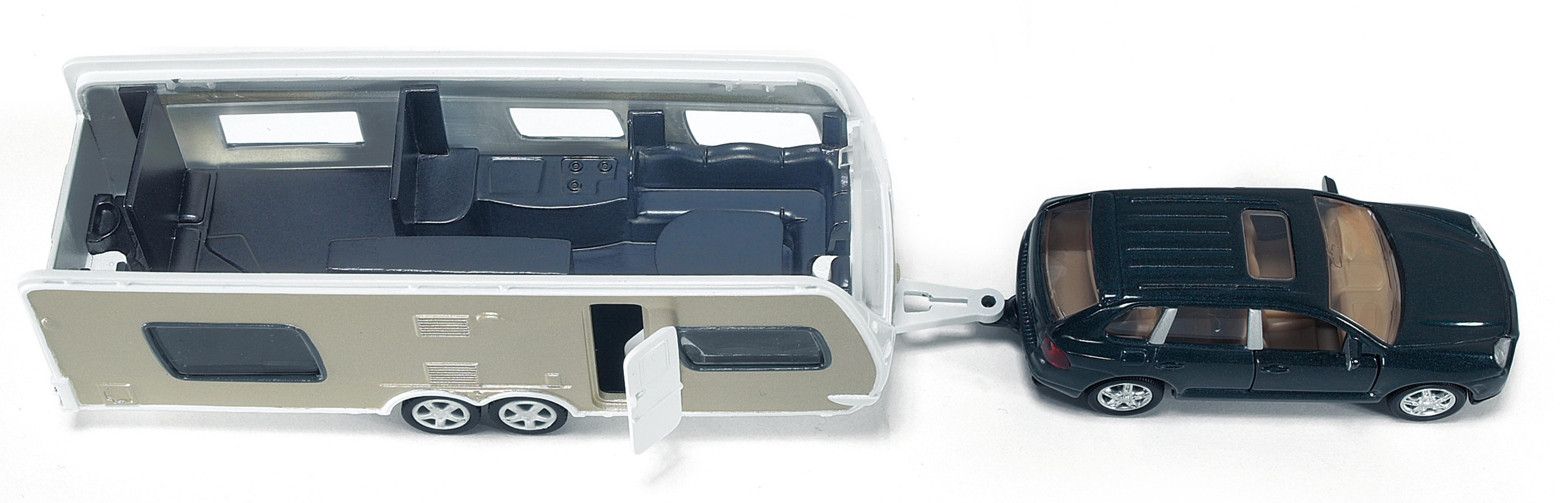 Spielzeugauto mit Wohnwagen. Wohnwagen-Innenraum sichtbar. Weißer Hintergrund.