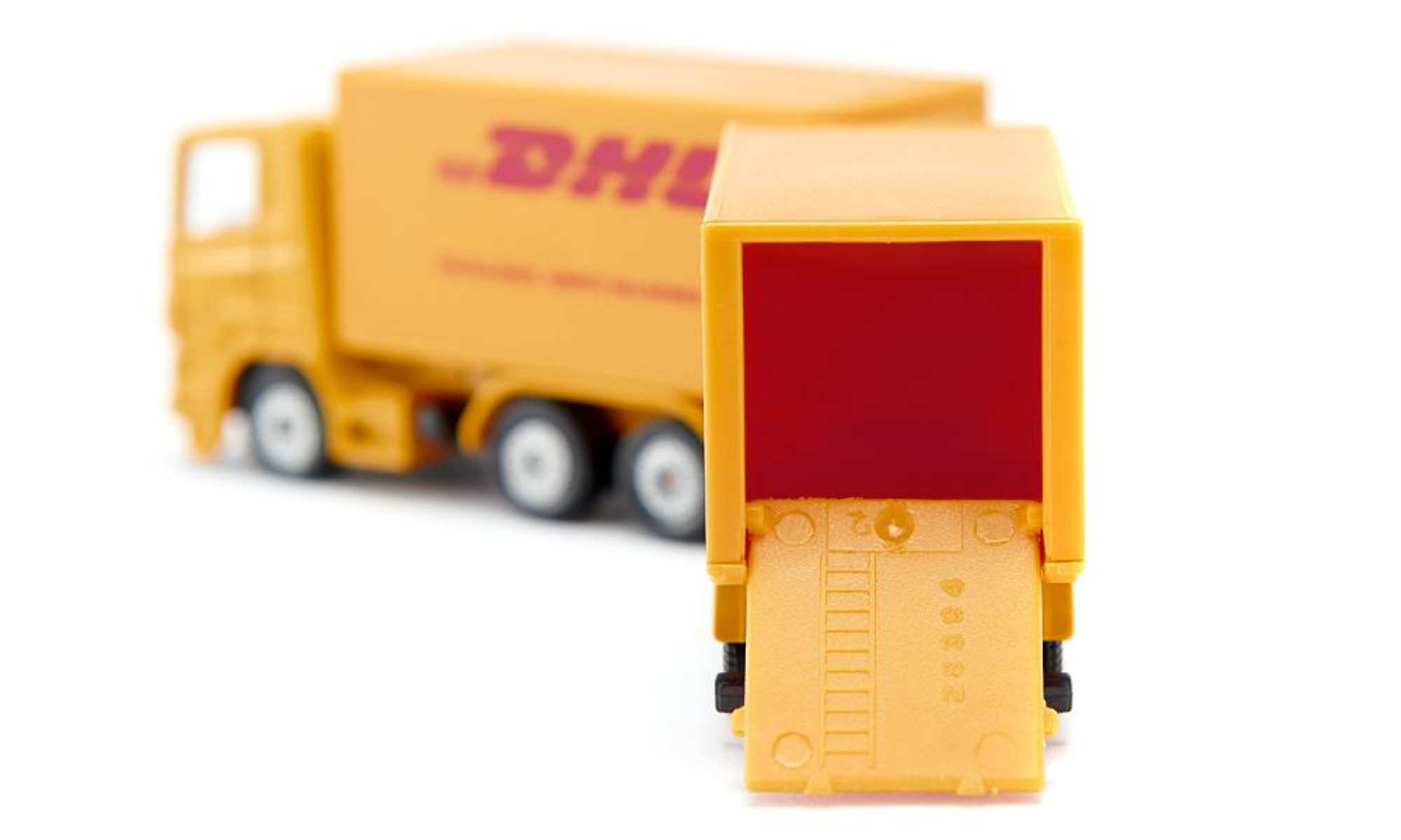 Ein DHL-LKW-Spielzeug mit einem geöffneten Container, der das Innere zeigt. Der LKW ist gelb.
