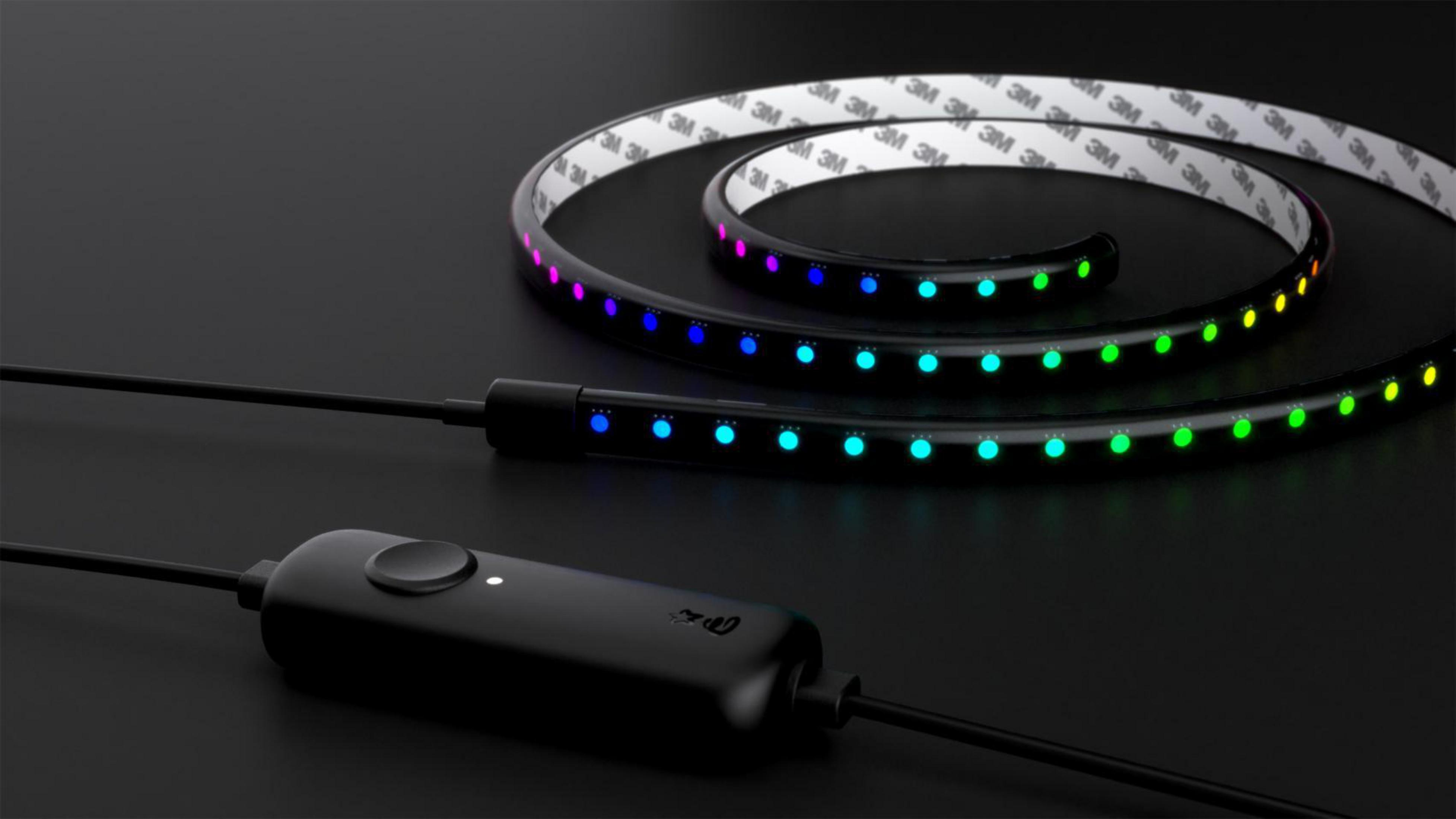 Une bande LED noire avec des lumières colorées sur une surface noire. Un contrôleur est également visible.