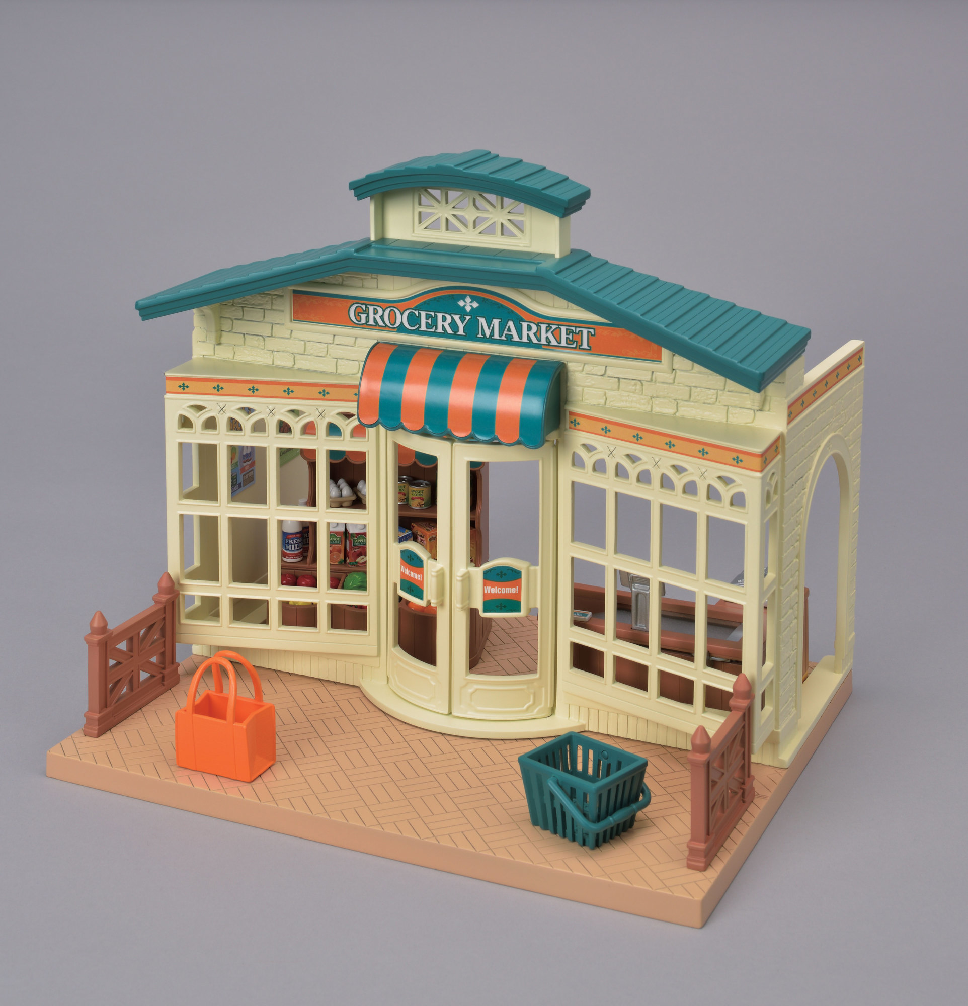 Miniaturowy model sklepu spożywczego. Ma zielony dach, witający znak i pomarańczową torbę na zakupy.