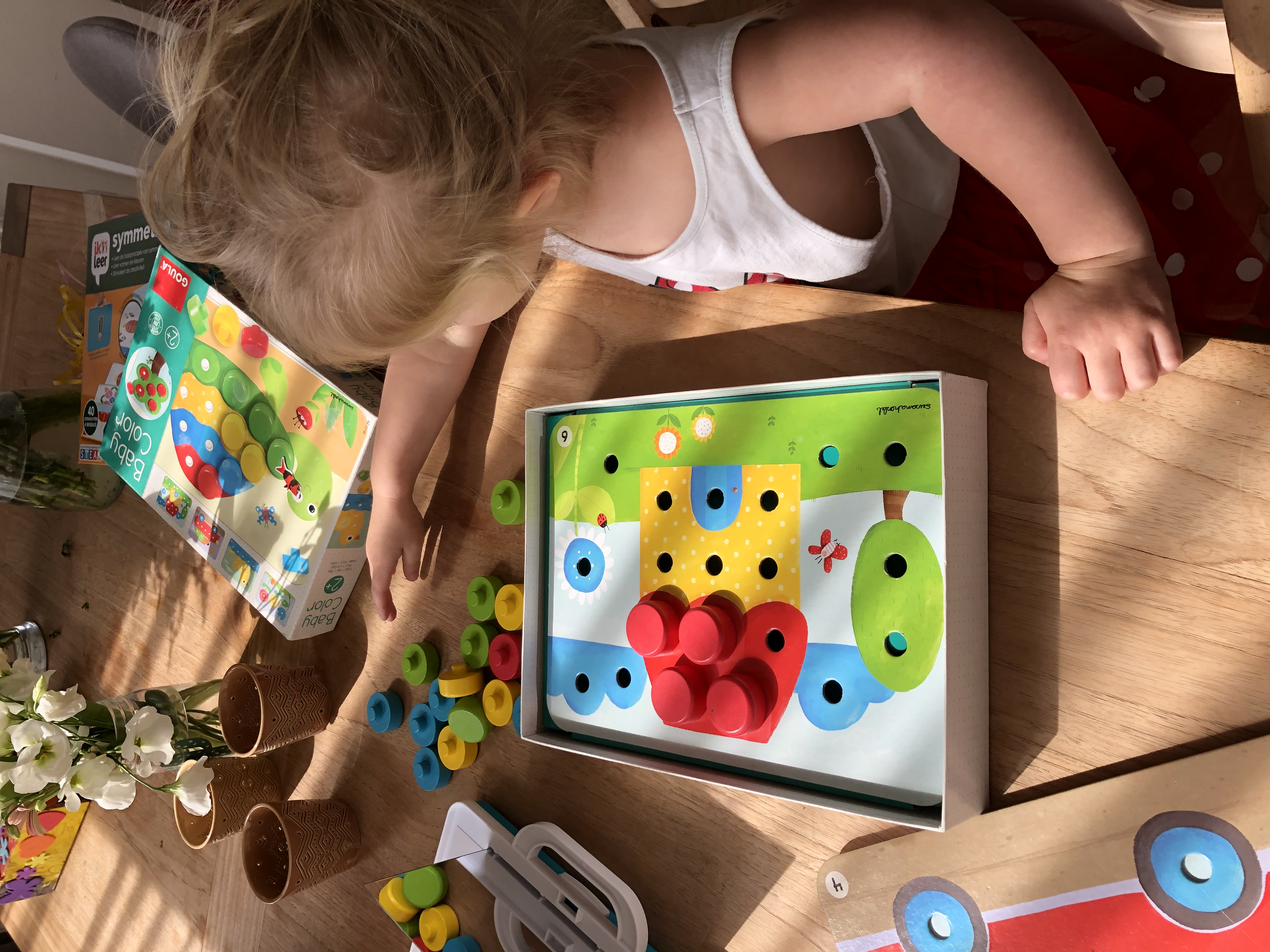 Dziecko bawiące się zabawką. Kolorowa zabawka na stole, słoneczne tło.